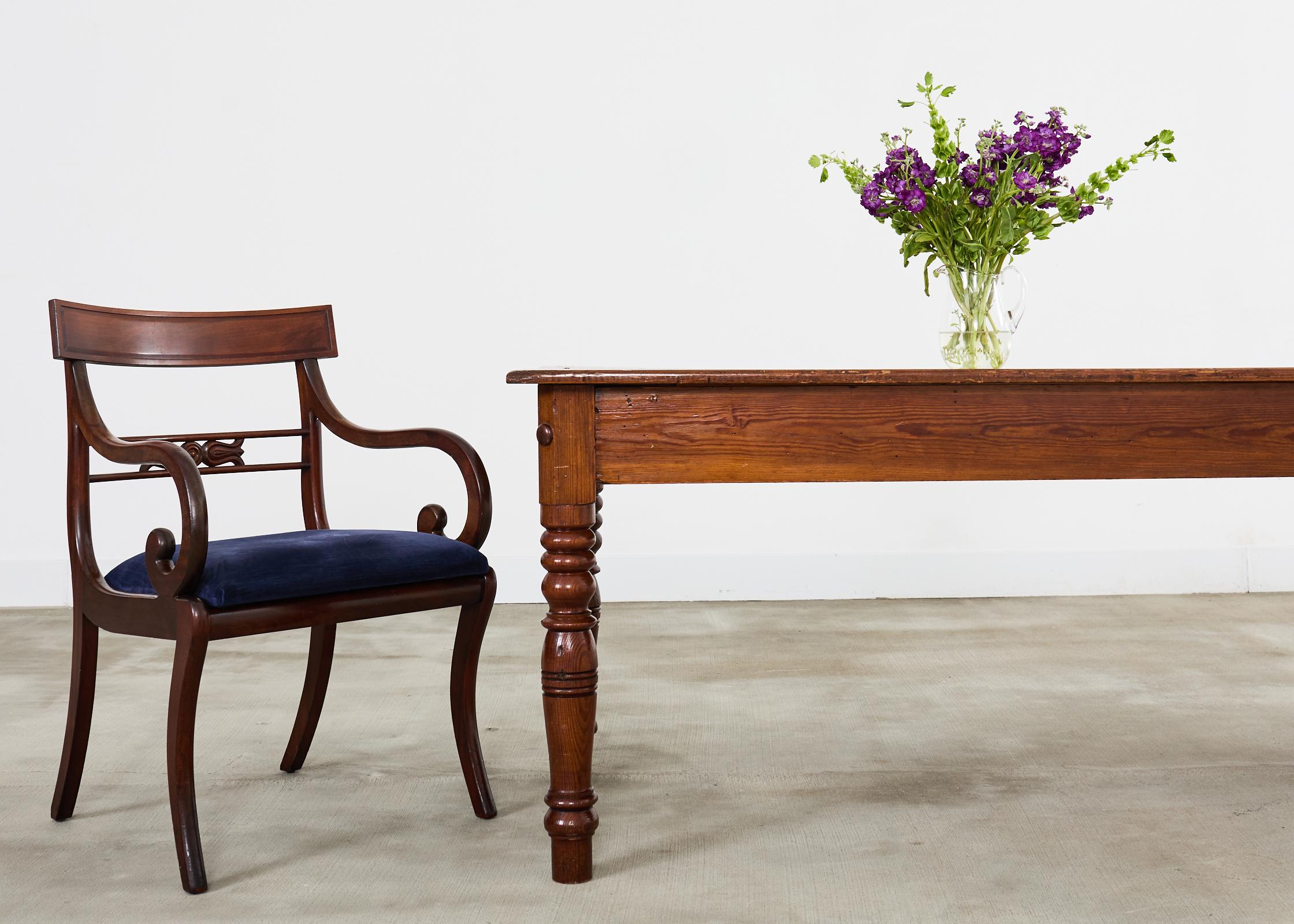 Grand country English farmhouse dining table or harvest table crafted on a monumental scale. The table measures nearly 12 feet long and features a three board top with long planks measuring 1 inch thick. The table is supported by distinctive turned