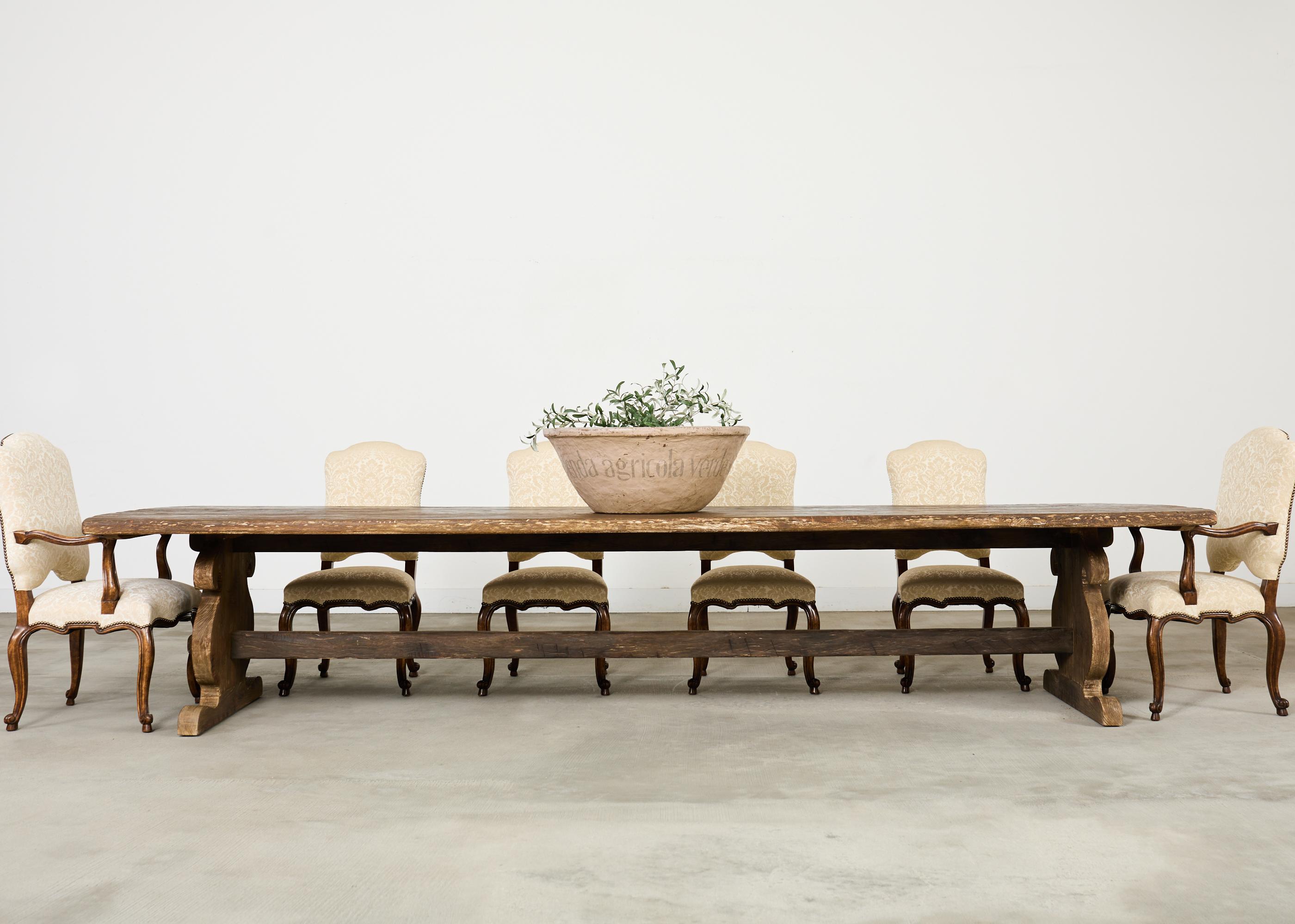 Mesa de comedor de granja palaciega de estilo provincial francés, elaborada a gran escala y de más de 4 metros de largo. La enorme tapa de tablones tiene los extremos sutilmente redondeados o curvados y se apoya en una enorme base de caballete. El