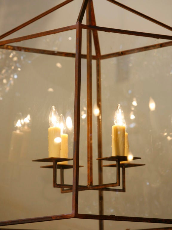 This timeless, large-scale, iron lantern is blacksmith made with tempered glass. It comes with a handmade iron canopy and three feet of iron interlocking shepherd hooks. Custom hand-forged iron bobeche and cluster with four Edison sockets. Newly