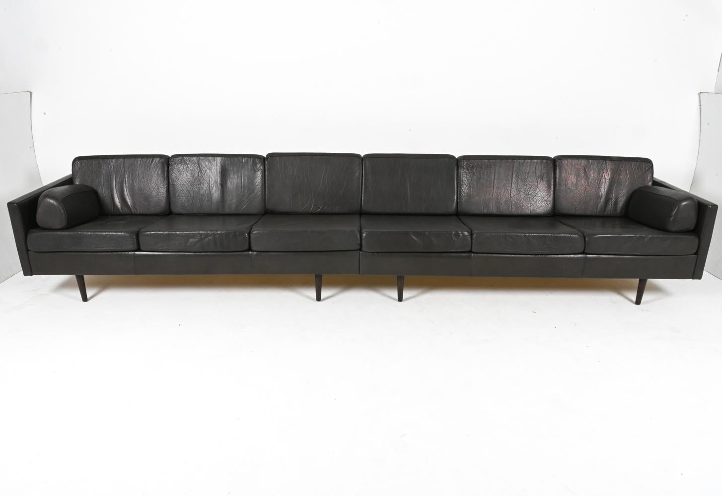 Immerse yourself in luxury and comfort with this expansive and monumental Danish leather sofa, a true statement piece crafted in the heart of the Mid-Century Modern era (circa 1960s). This grand sofa boasts a robust oak frame, its warm tones a