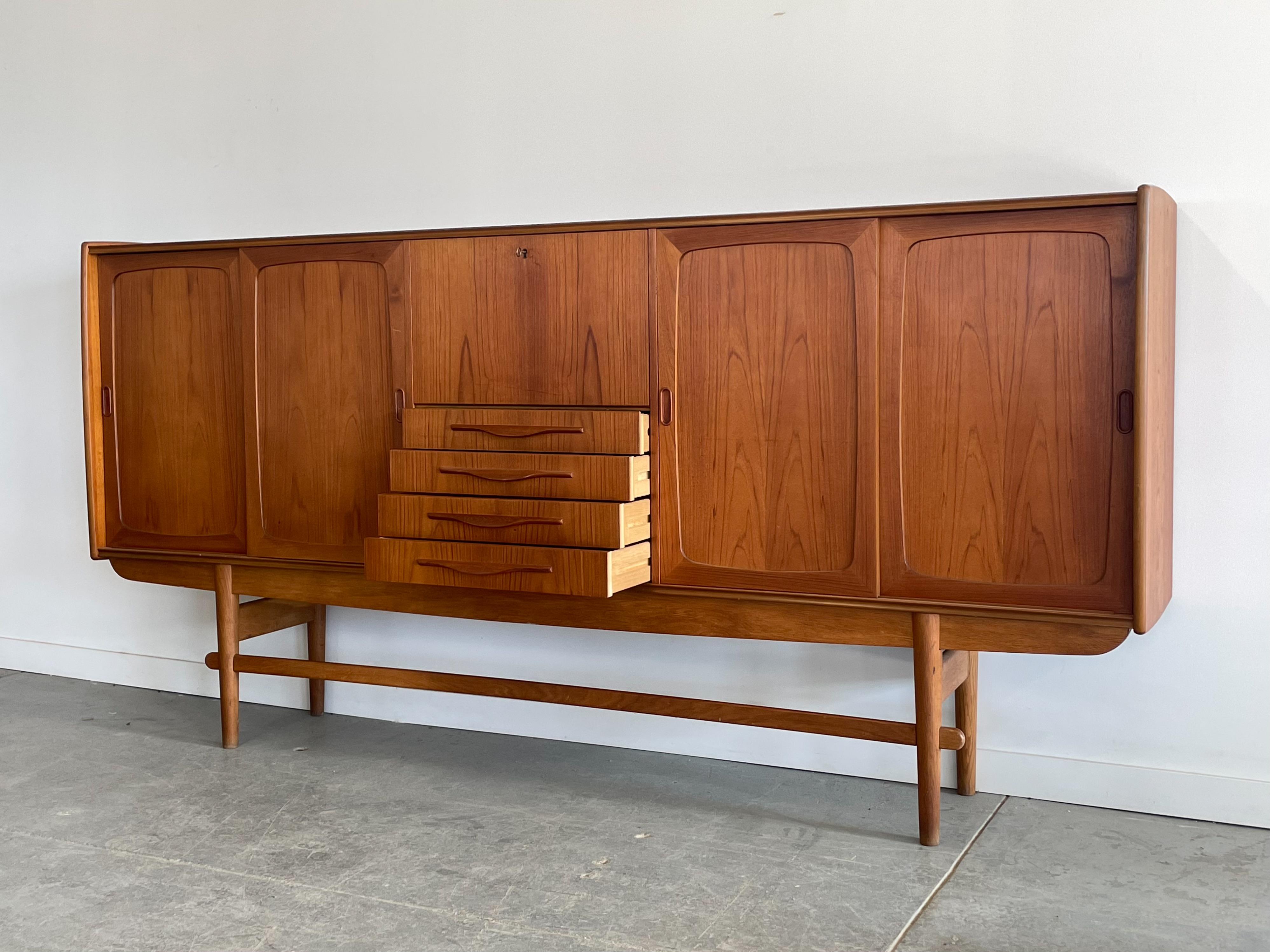 Monumental teak highboard with oak base by Holger Christiansen, Denmark. This massive storage piece offers adjustable shelving, drawers, and a drop down bar cabinet. The construction and detailing is top-notch throughout. This piece features