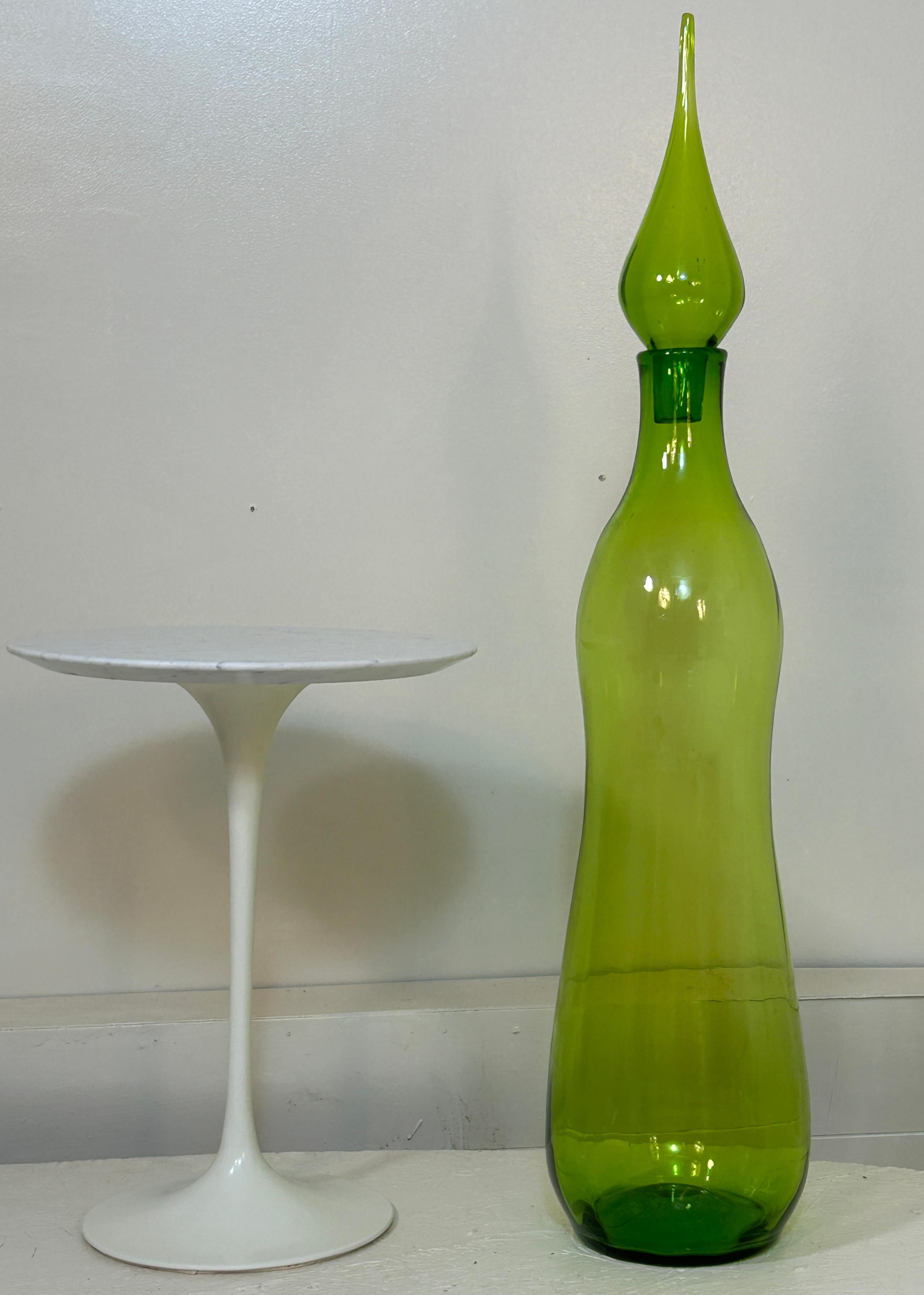 Creato da John Nickerson nel 1972 per Blenko, questo decanter da pavimento di dimensioni monumentali, il modello 7235, è stato prodotto con e senza il tappo a goccia; entrambi i modelli possono essere utilizzati come vasi da pavimento, se lo si