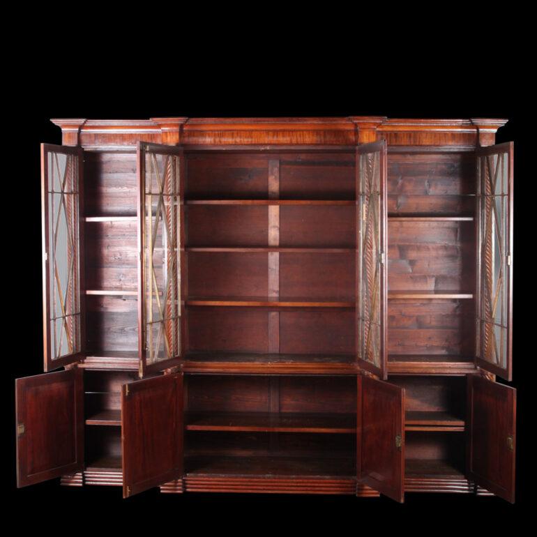Large 19th Century Irish William IV mahogany  bookcase.  Stunning pierced lattice work, cresting above four geometric glazed doors, with shelved interior over four fielded cupboard doors and outset plinth base.