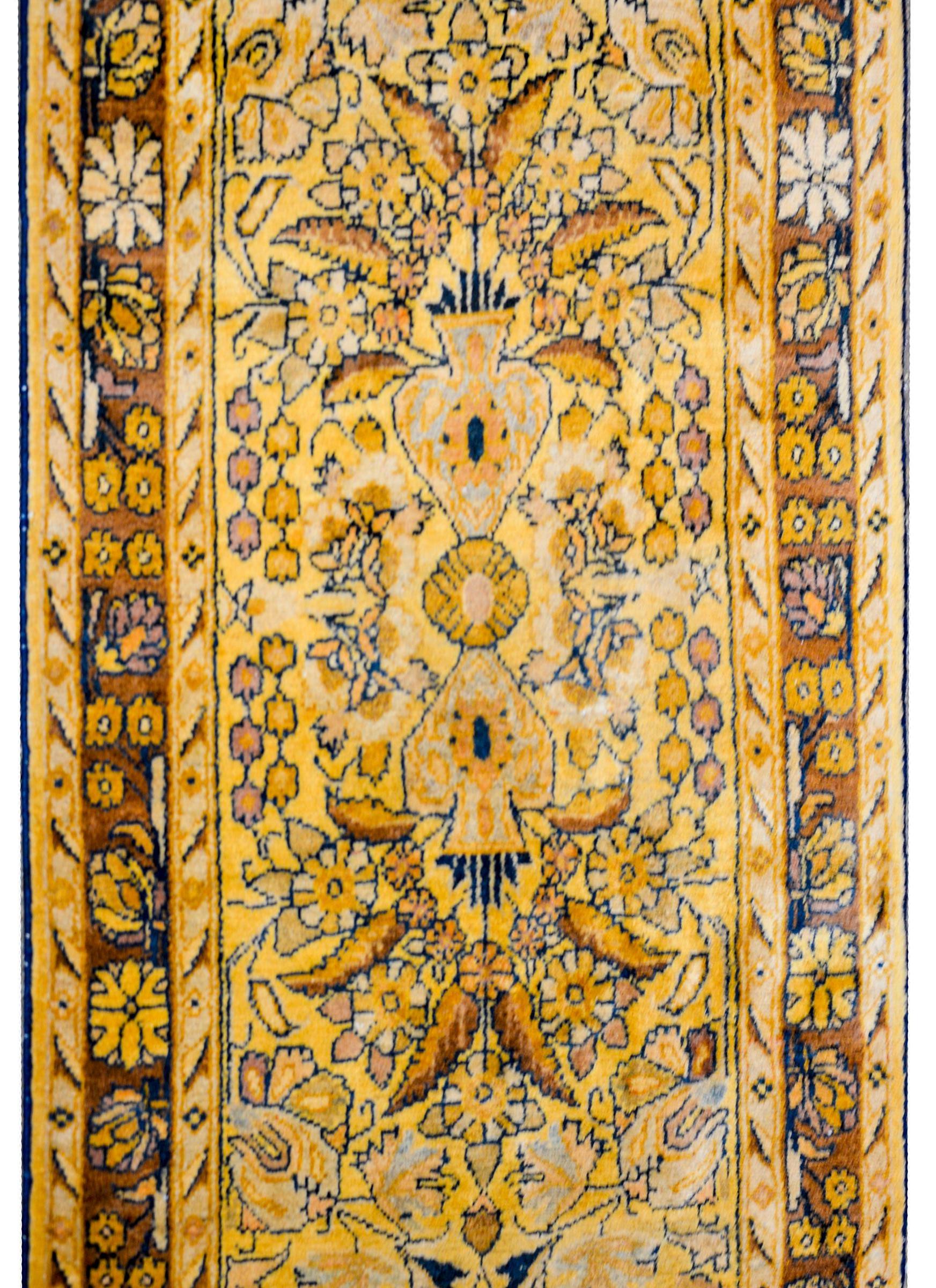 A monumental early 20th century Lilihan runner with a fantastic pattern of mirrored vases with flowers woven in gold, light and dark indigo, and brown wool, on a brilliant gold background. The border is wonderful with a large-scale floral pattern on