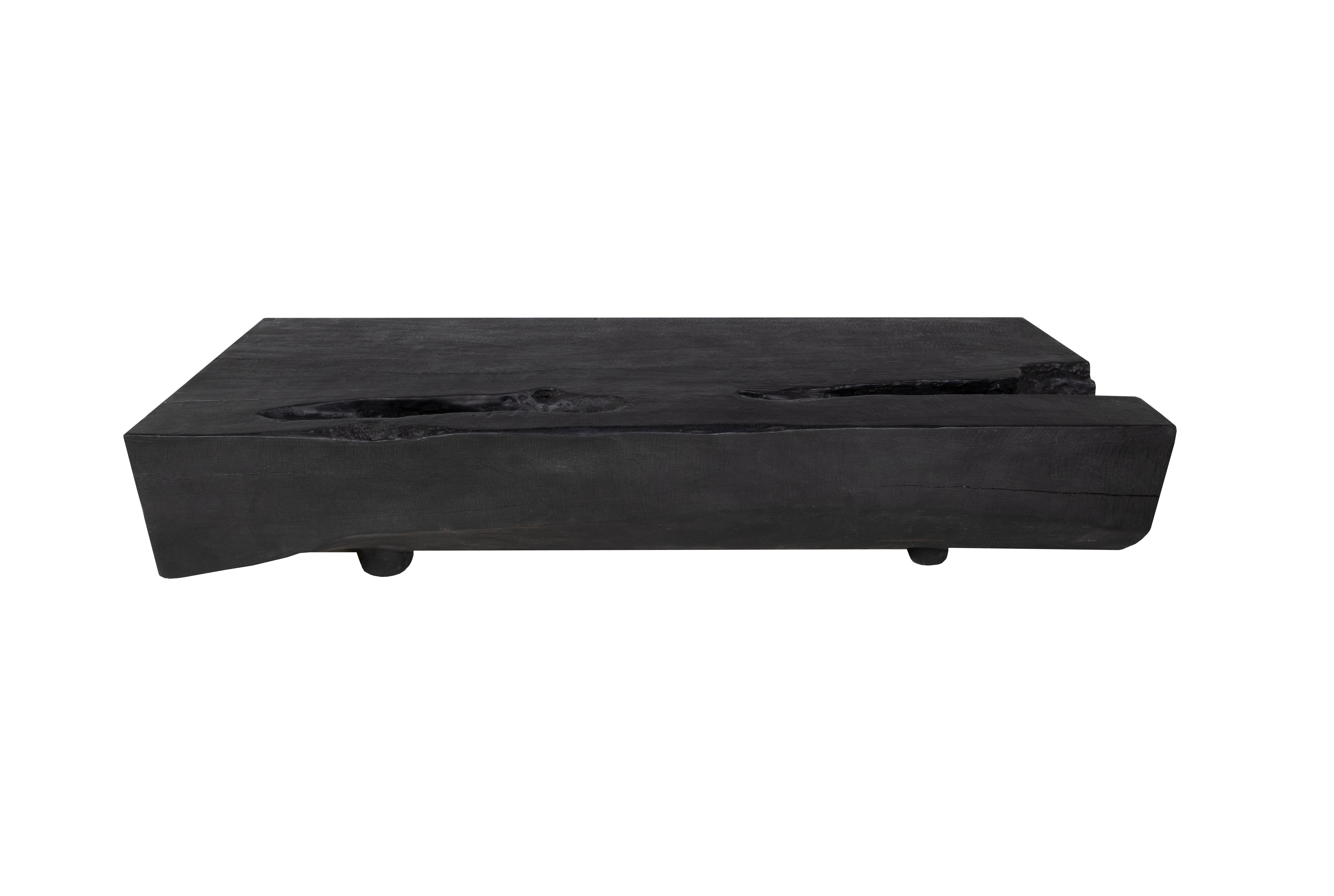 This monumental block coffee table is built from one single block of lychee hardwood. The top is flattened, sanded, and stained black to compliment the wood's naturally rich texture and rustic patterns. The sides are kept in their natural organic