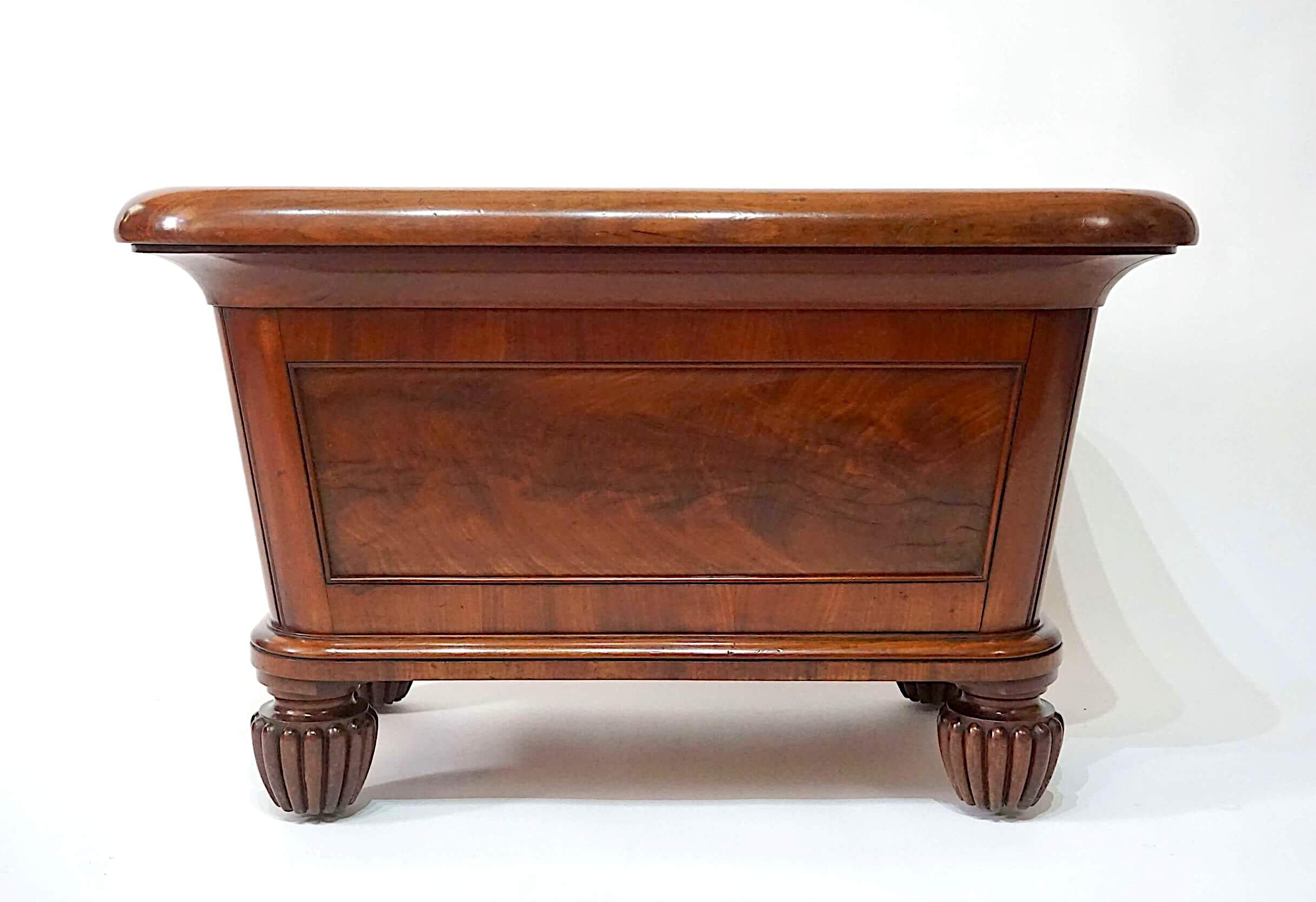 A magnificent English circa 1830, George IV / William IV period neoclassical mahogany champagne cooler of monumental scale and sarcophagus form, the thick rounded-edge 'cushion' rim above original lead lined interior, the exterior panelled with