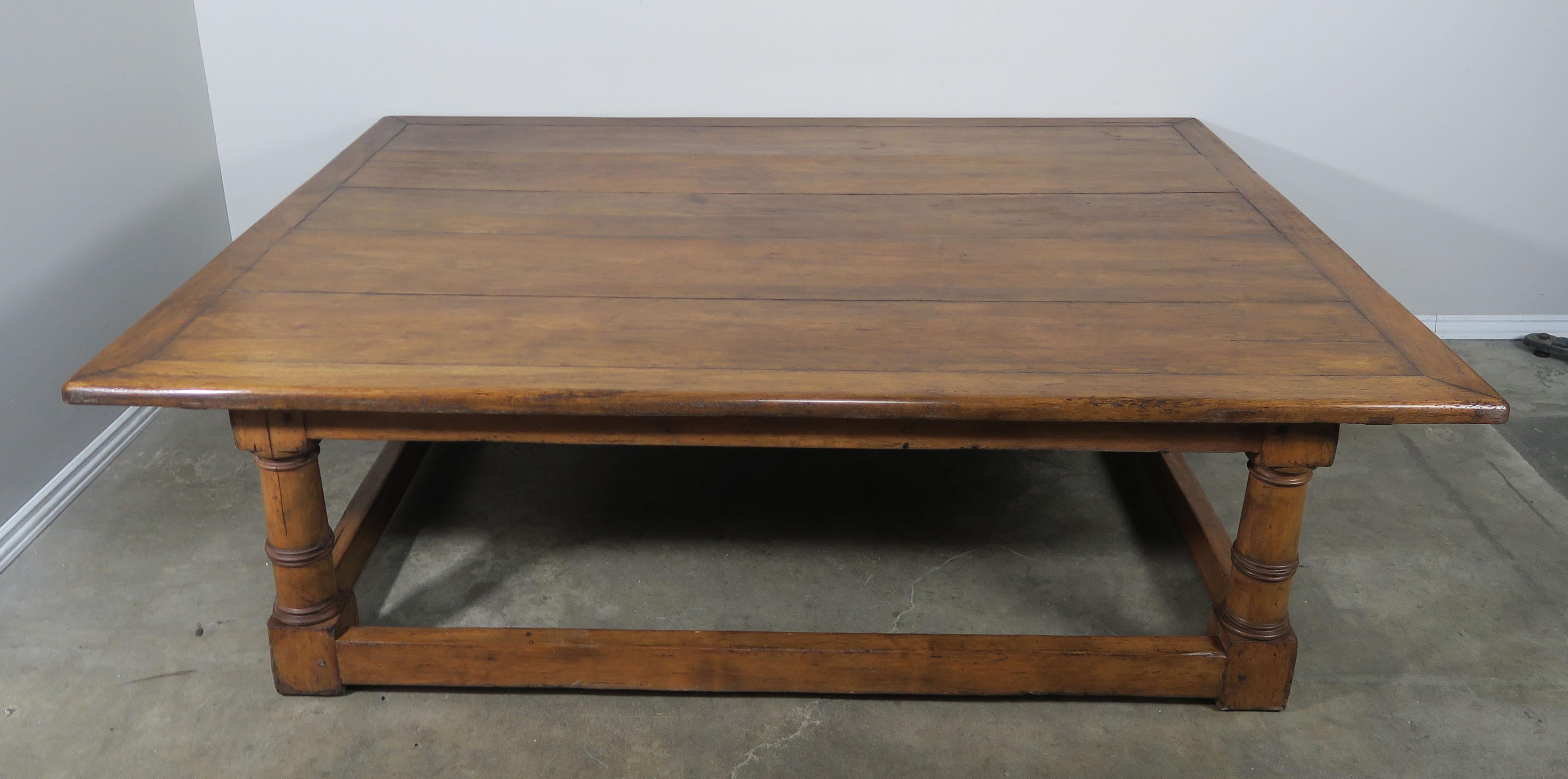 Monumental English rectangular shaped walnut coffee table standing on four column legs connected by a bottom stretcher. Beautiful patina from years of use.