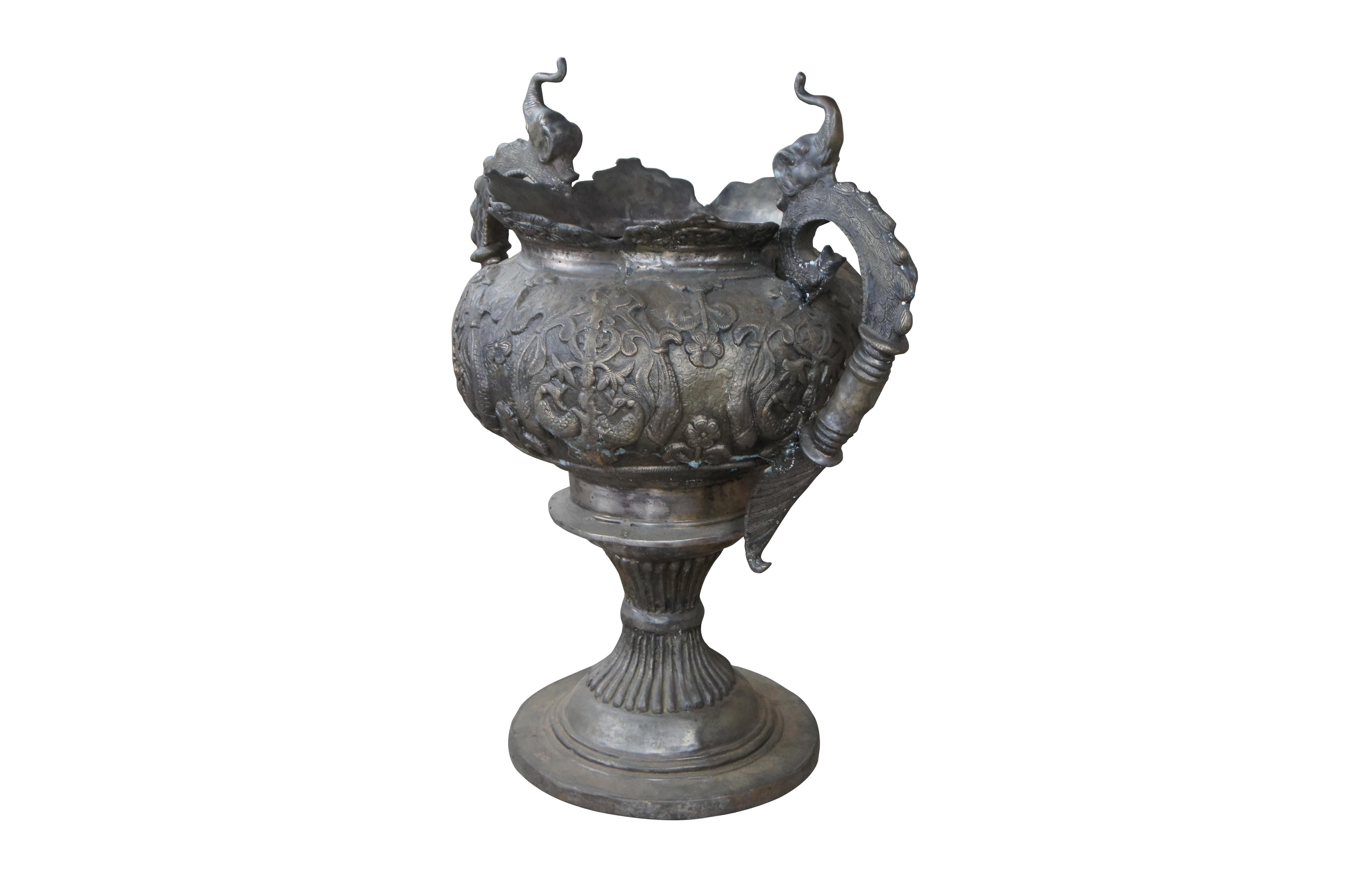 A large 20th century antiqued Indian bronze footed floor urn or planter. Features figural elephants over Phoenix / Griffin / Peacock handles. The body is decorated with birds and floral motifs over a reeded and footed base. Great for use inside your