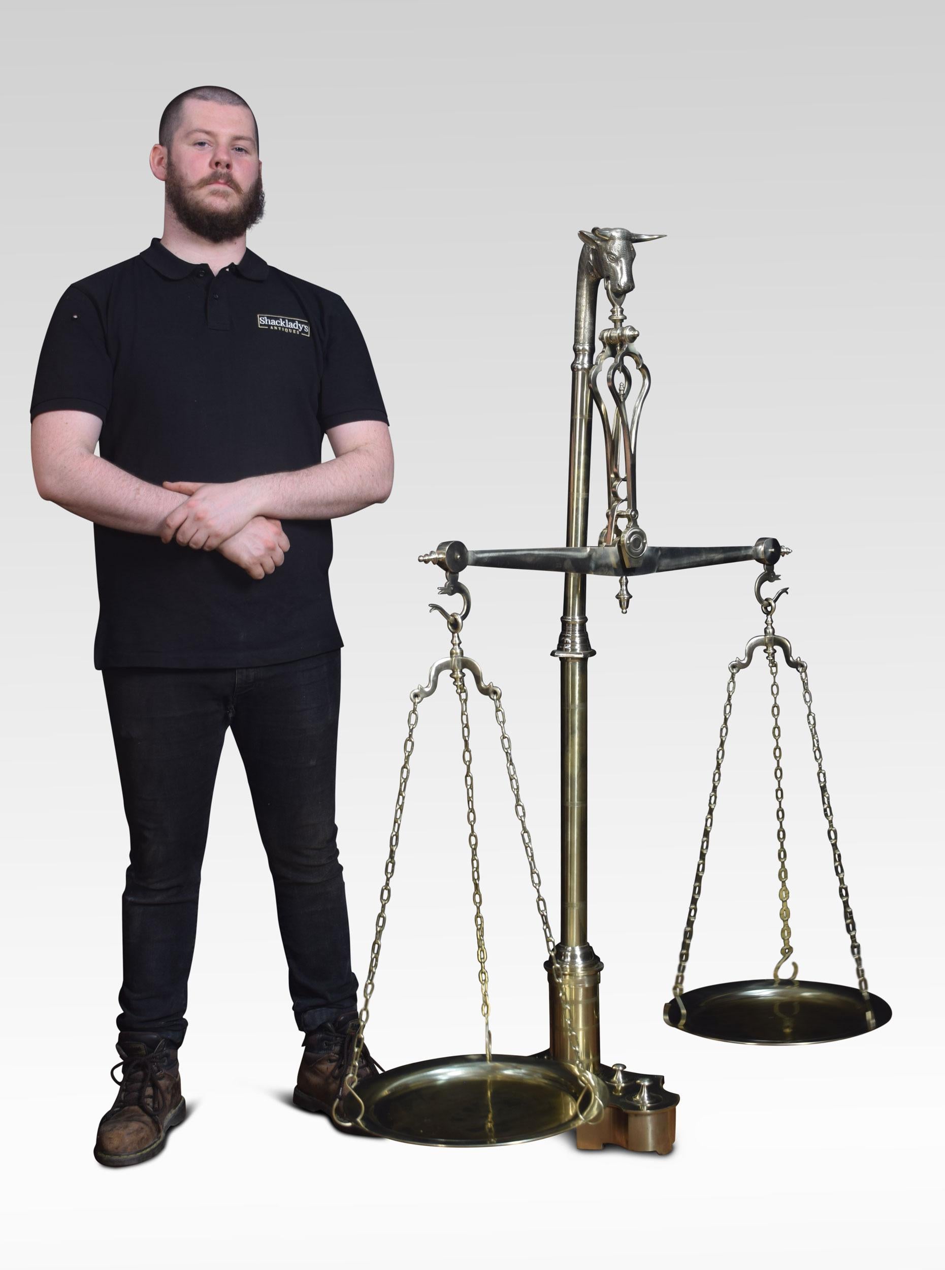 A large set of floor standing brass balance scales and graduated weights with bullhead terminal above the circular column, to the platform base with fourteen graduated compartments for each original weight.
Dimensions:
Height 61 inches
Width 46