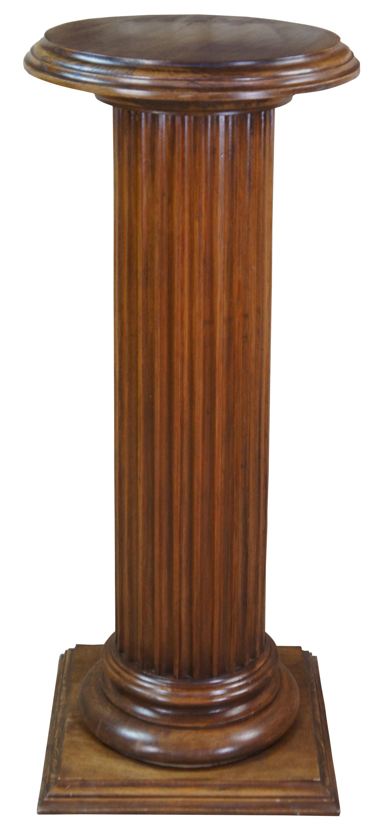Monumental oak Corinthian pedestal or plant stand featuring a fluted column, square base and round top. Measure: 44