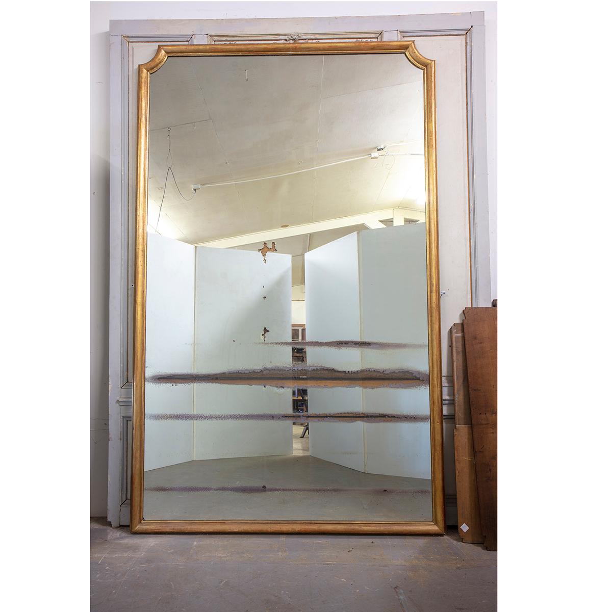 This is a massive French 19th century mirror from the main hall of the Archbishop Palace Rouen, Normandy, France. This mirror is over 10’ tall and more than 6’ wide. Both the frame and mirror show aging. The original mercury mirror plate has