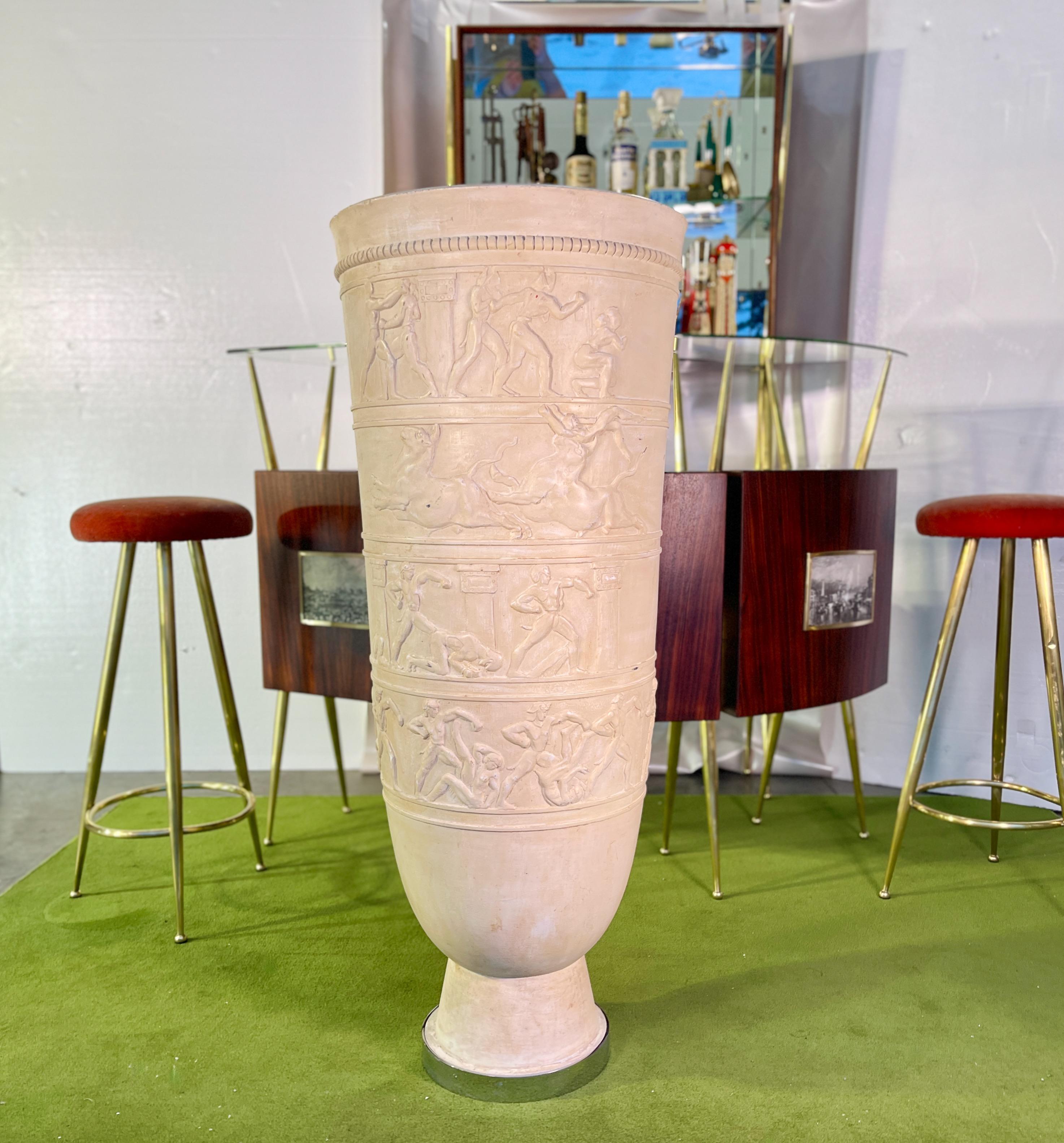 Monumental scale French Art Deco urn with bas relief on one side made of a plaster composite c, 1930. 
Urn is vase form with an elongated taper on a narrow round foot which is banded in hefty nickel plated brass. 
Fitted inside with a standard