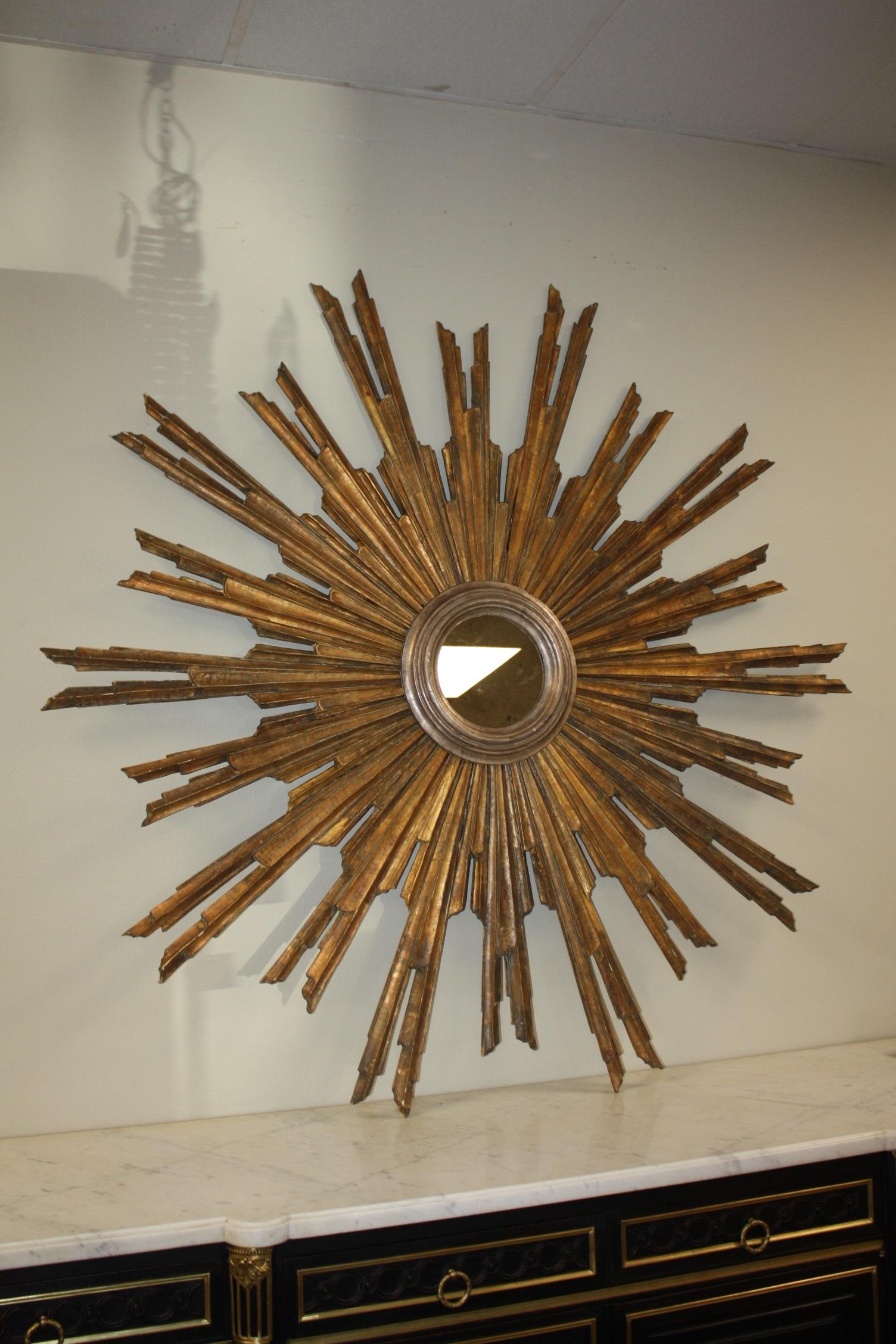 A large French gilt sunburst (or starburst) with mirrored glass center in molded frame, 63