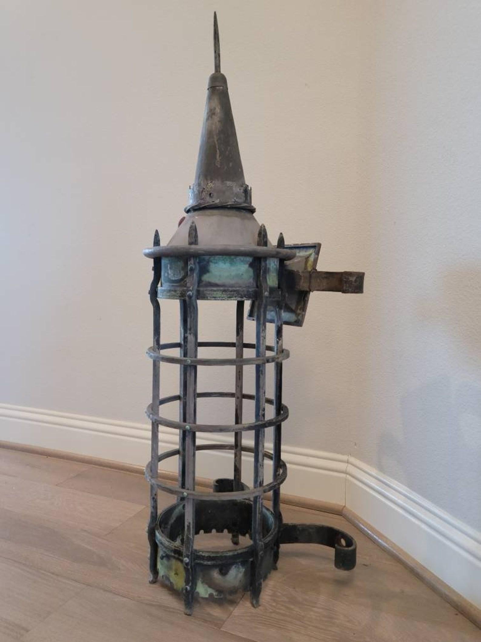 A magnificent French Gothic Revival outdoor lantern. 

The monumental size sconce with beautiful verdigris patina finish features a tall architectural iron cage body topped with an elongated needle-spire emerging from steeple tower surrounded by a