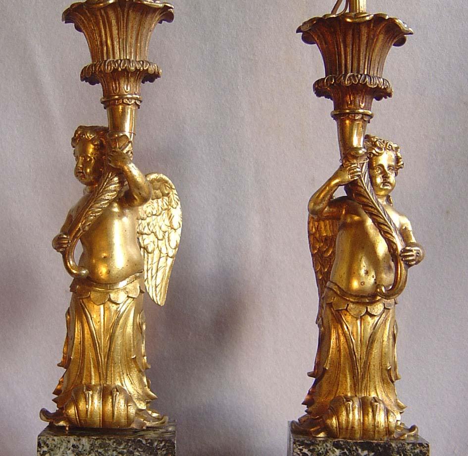A monumental pair of French lamps in antique vert marble and gilt bronze. Set on large antique vert marble bases with gilt bronze mouldings. The lamp holders are in the form of the bust and torso of winged children terminating in Acanthuus scrolls.