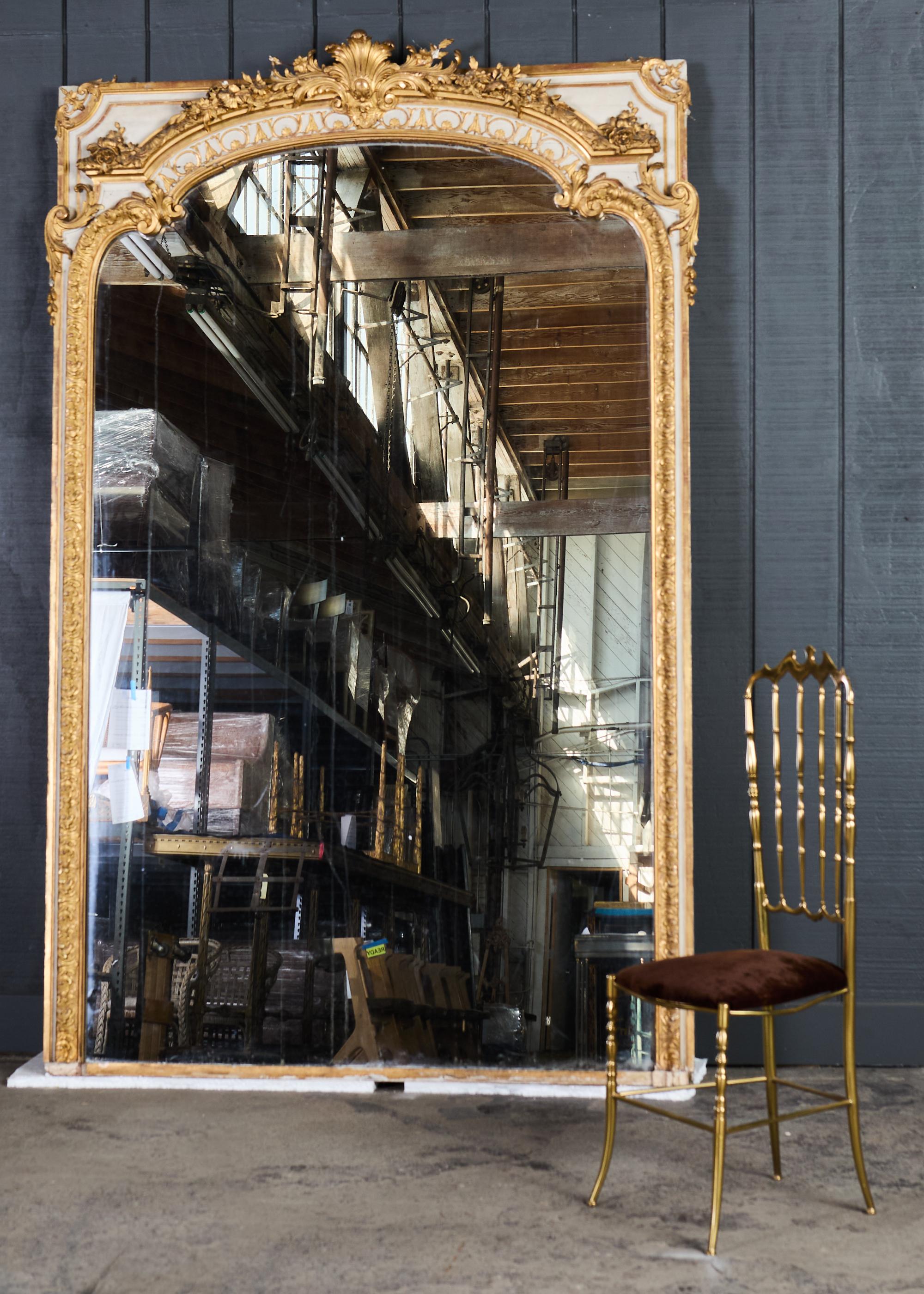 Miroir de sol en bois doré de la fin du 19e siècle, de style Louis XV. Le miroir possède un grand cadre peint en bois, orné de décorations florales, de feuillages et d'acanthes en volutes. Le plateau présente une moulure de corniche en haut-relief