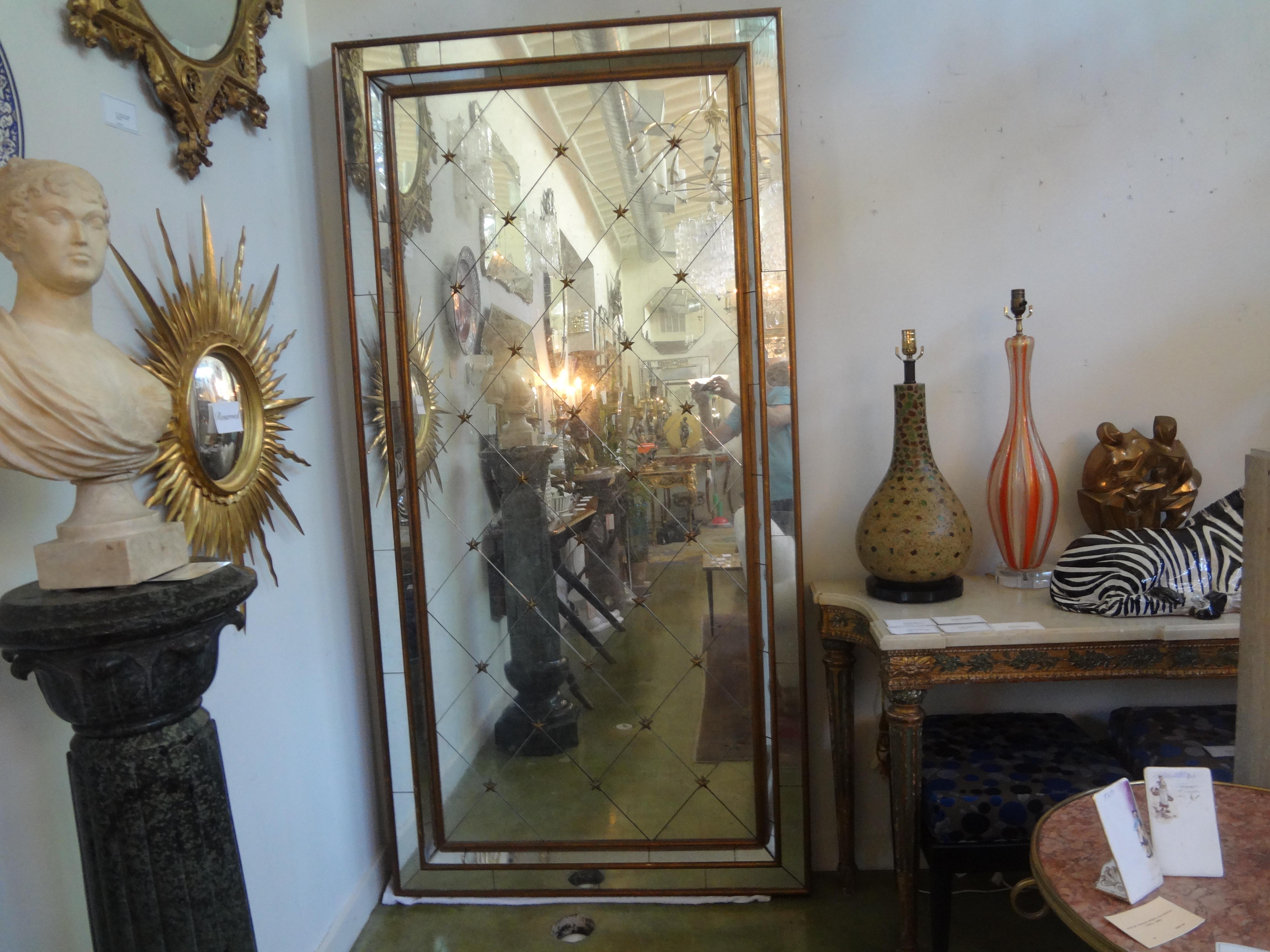 Monumental French Maison Jansen Style Mirror.
This stunning full length mirror is giltwood framed with a central area of diamond shaped mirror panels separated by gilt metal stars and a border of mirrored panels.
This outstanding Hollywood Regency