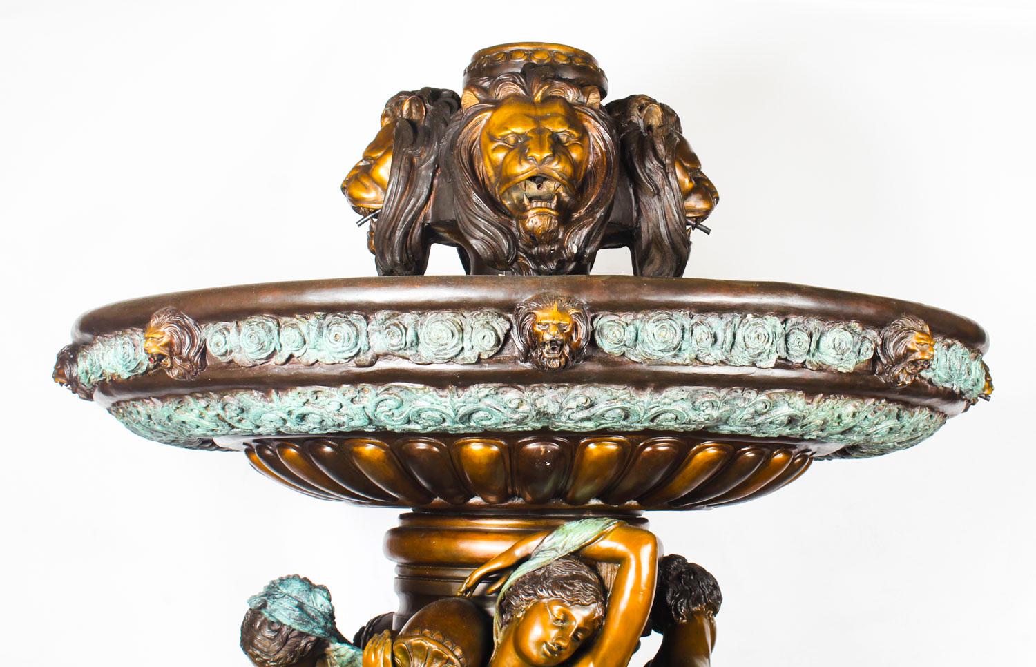 This is a monumental two-tier fountain sculpted in bronze in the neo-classical style, dating from the late 20th century.
 
This formidable fountain sprays water out of the top and out of four large roaring lion head cartouches. The water goes into