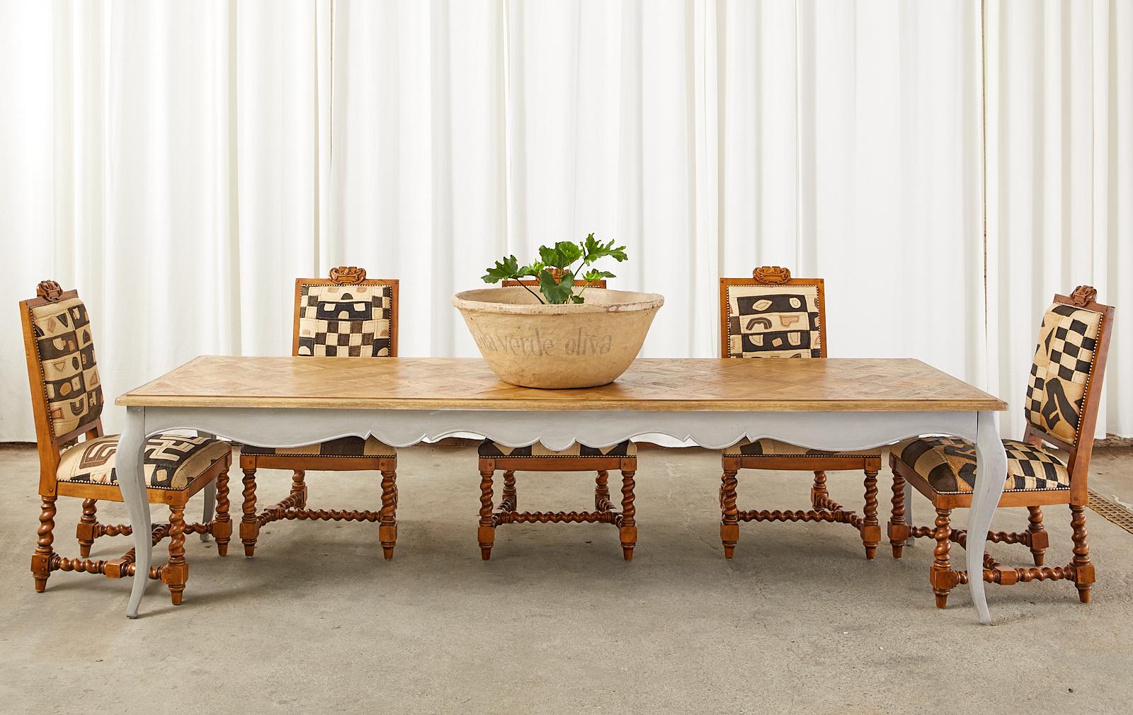 Country French provincial style dining or harvest farm table by Sarreid LTD. Monumental scale nearly 10 feet long featuring a dramatic hand-crafted oak parquet top. The table base has a scalloped apron supported by elegant cabriole legs all finished