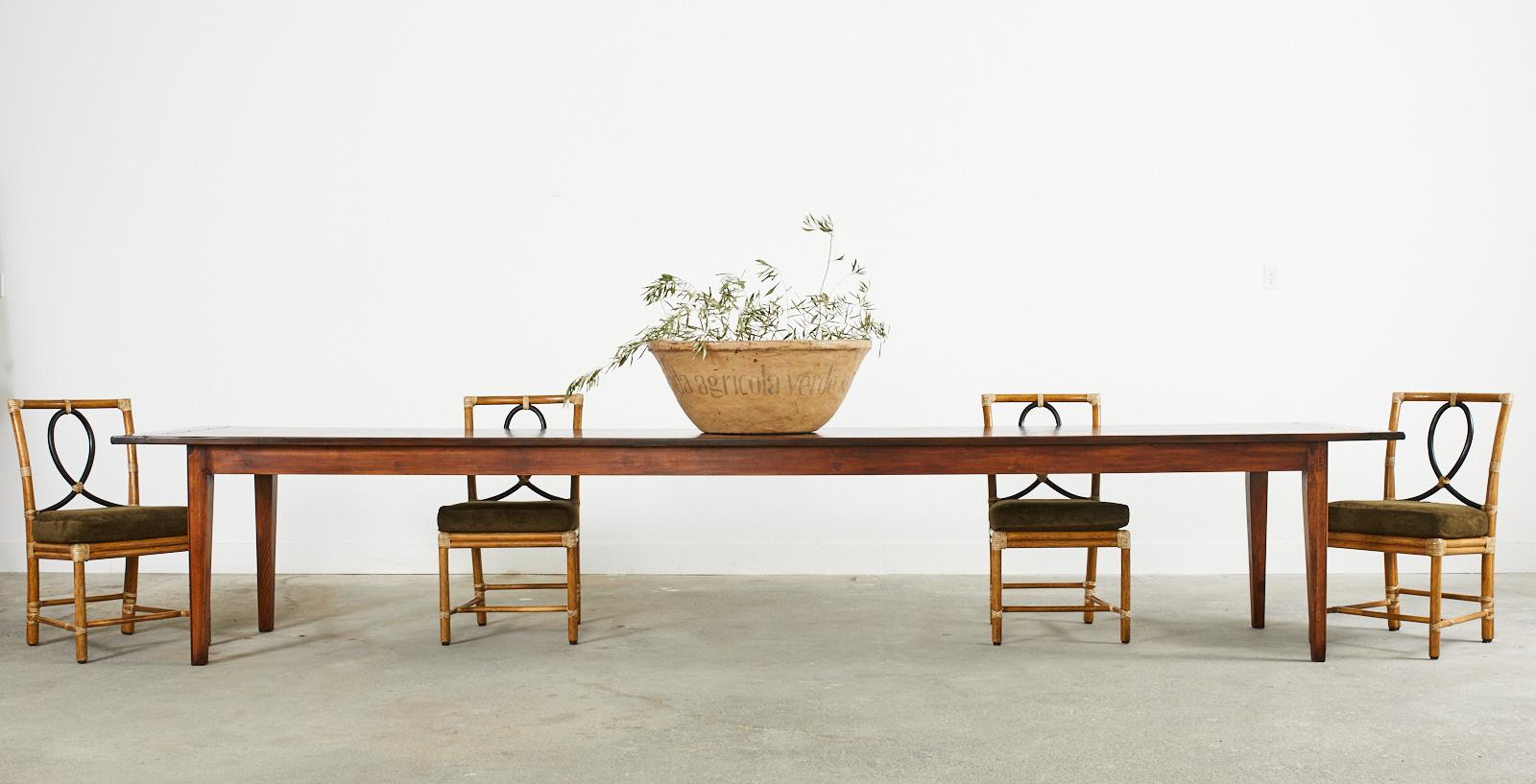 The quintessential French provincial farmhouse dining or harvest table made on a monumental scale measuring nearly 14 feet long. The table features a long, thick walnut plank top measuring 1 inch thick with breadboard ends and peg construction