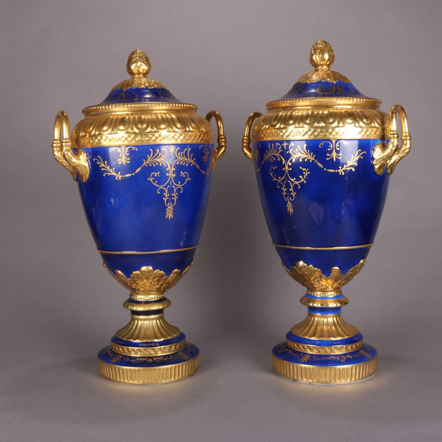 Pair of monumental French Serves School double handled footed and lidded urns feature heavily gilt foliate and scroll decoration on cobalt blue ground, style urns, 20th century

Measures: 24