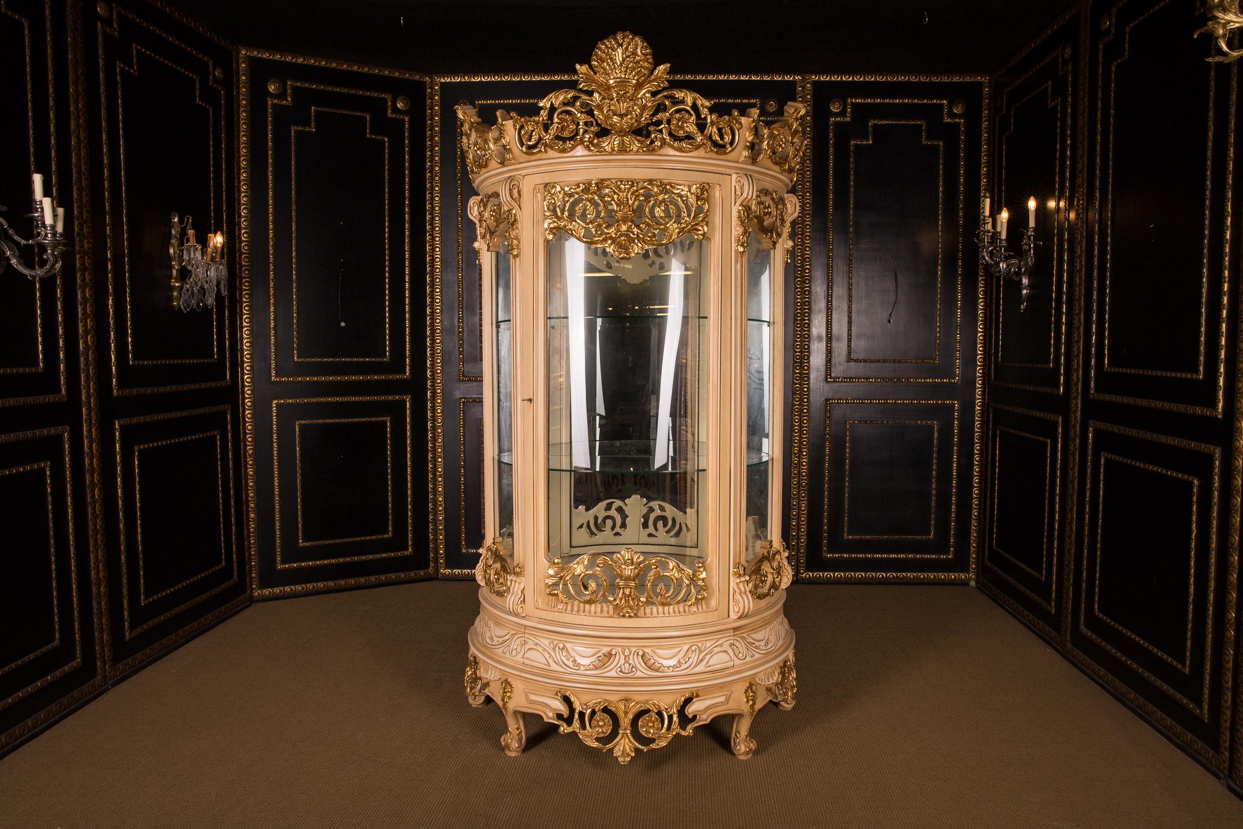 Massive, finely carved beech wood, colored and gilt gilded. High-rectangular, half-round and one-door cambered body, glazed from three sides. The entire showcase can be dismantled. On curved feet one-door scalloped frame. Back wall mirrored, three