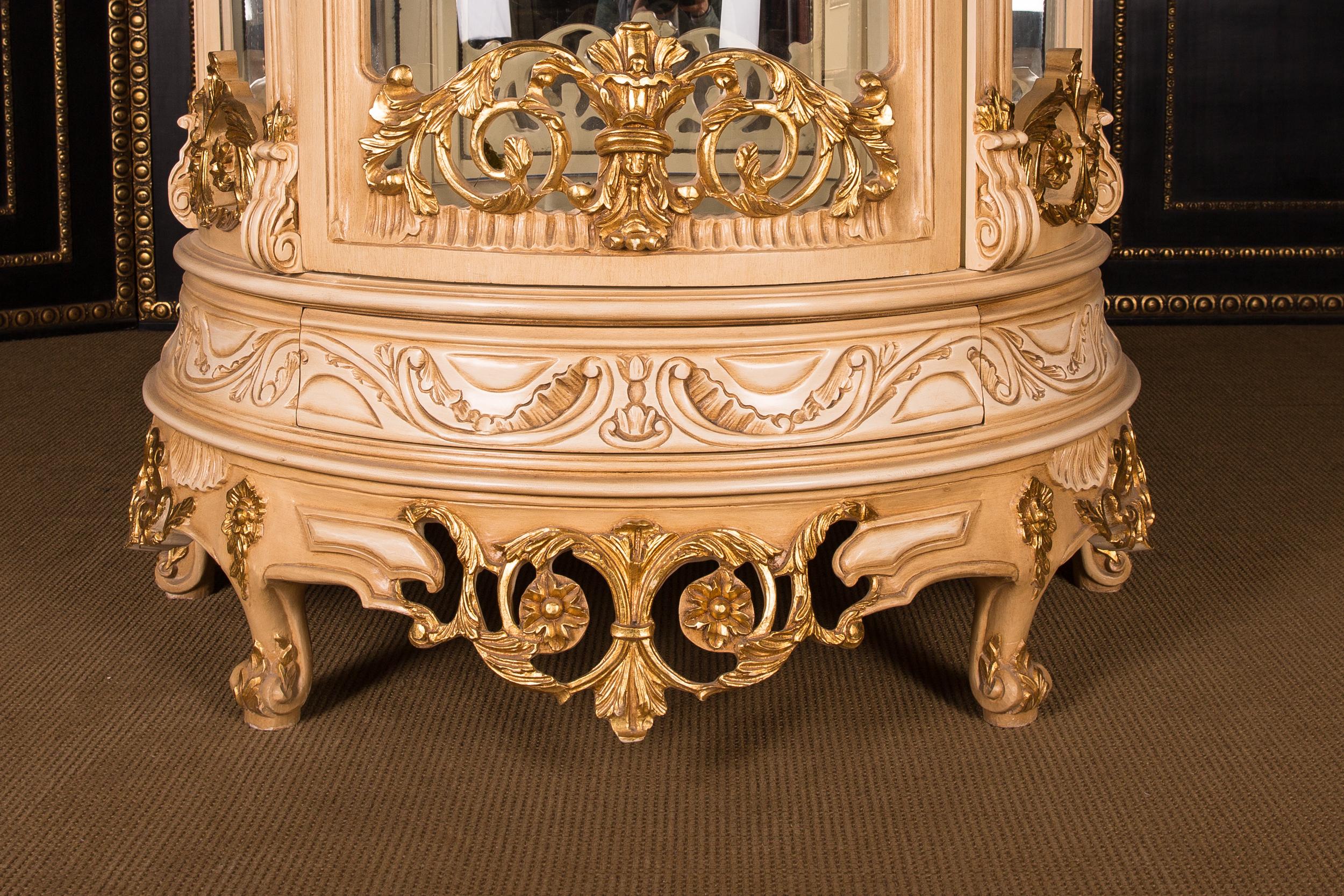 Massive, finely carved beechwood, colored and gilt gilded. High-rectangular, half-round and one-door cambered body, glazed from three sides. The entire showcase can be dismantled. On curved feet one-door scalloped frame. Back wall mirrored, three