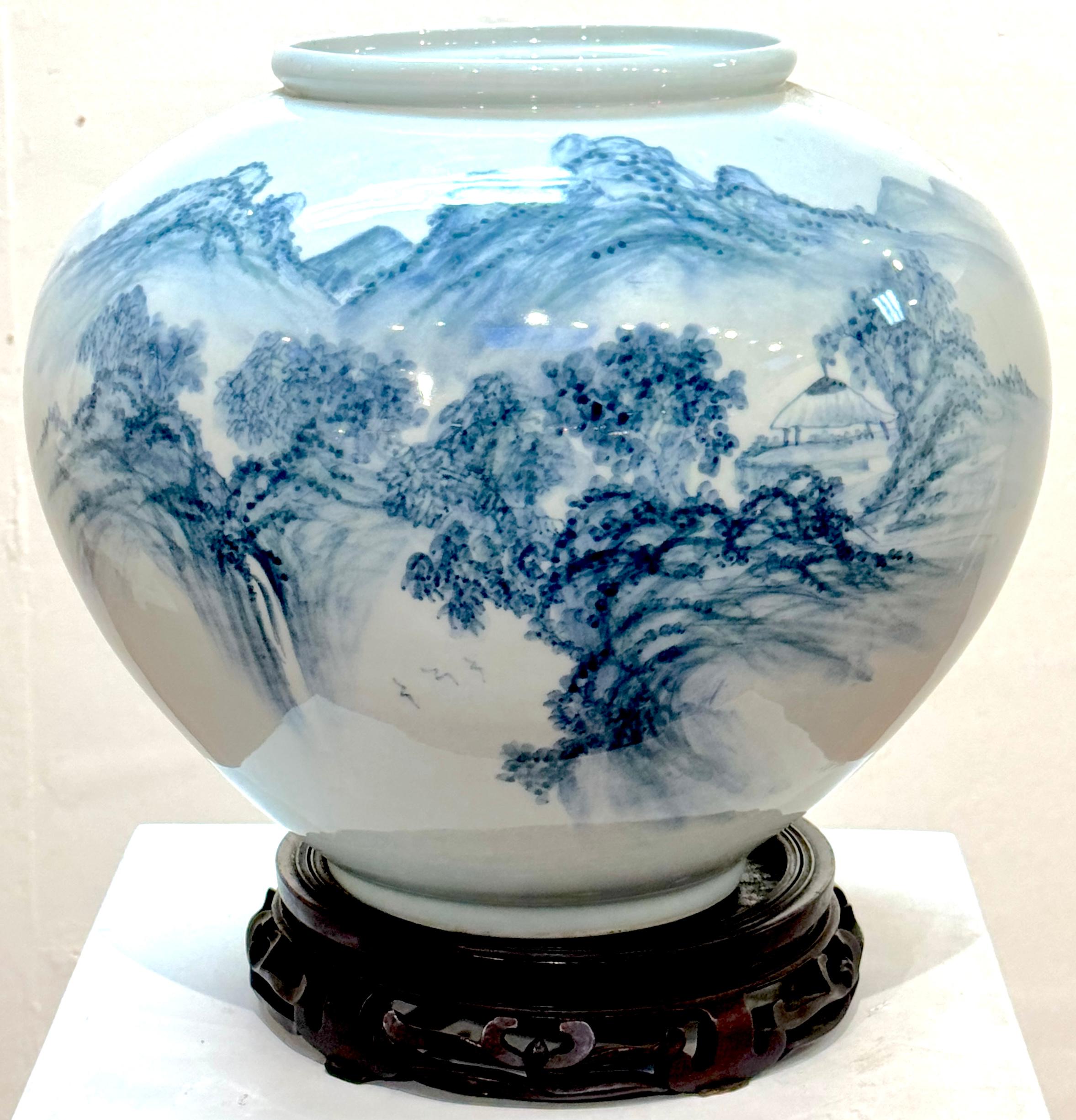 Monumental Fukagawa Blue and White Arita Landscape Vase, Signed, Circa Mid-20th Century, 2 pieces is the vase, the second item is exceptional carved hardwood stand. 

A striking and masterfully painted Japanese blue and white porcelain vase,