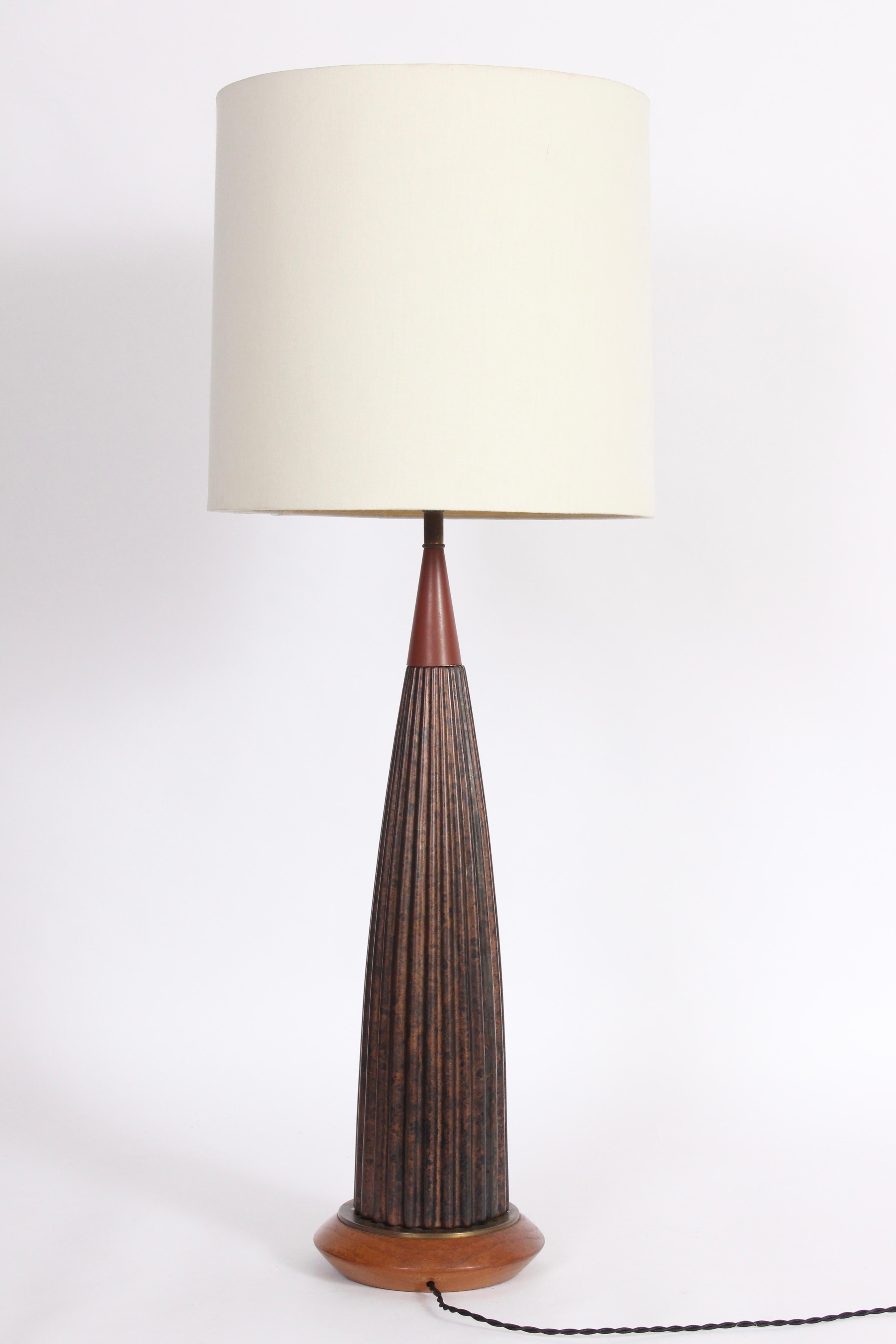 Tall Gerald Thurston attributed black and brown ribbed porcelain table lamp, 1950s. Featuring a missile form in dark bronze and silver glazed coloration detailed with wood neck and base. Shade shown for display only (13 H x 13 D top x 14 D bottom).