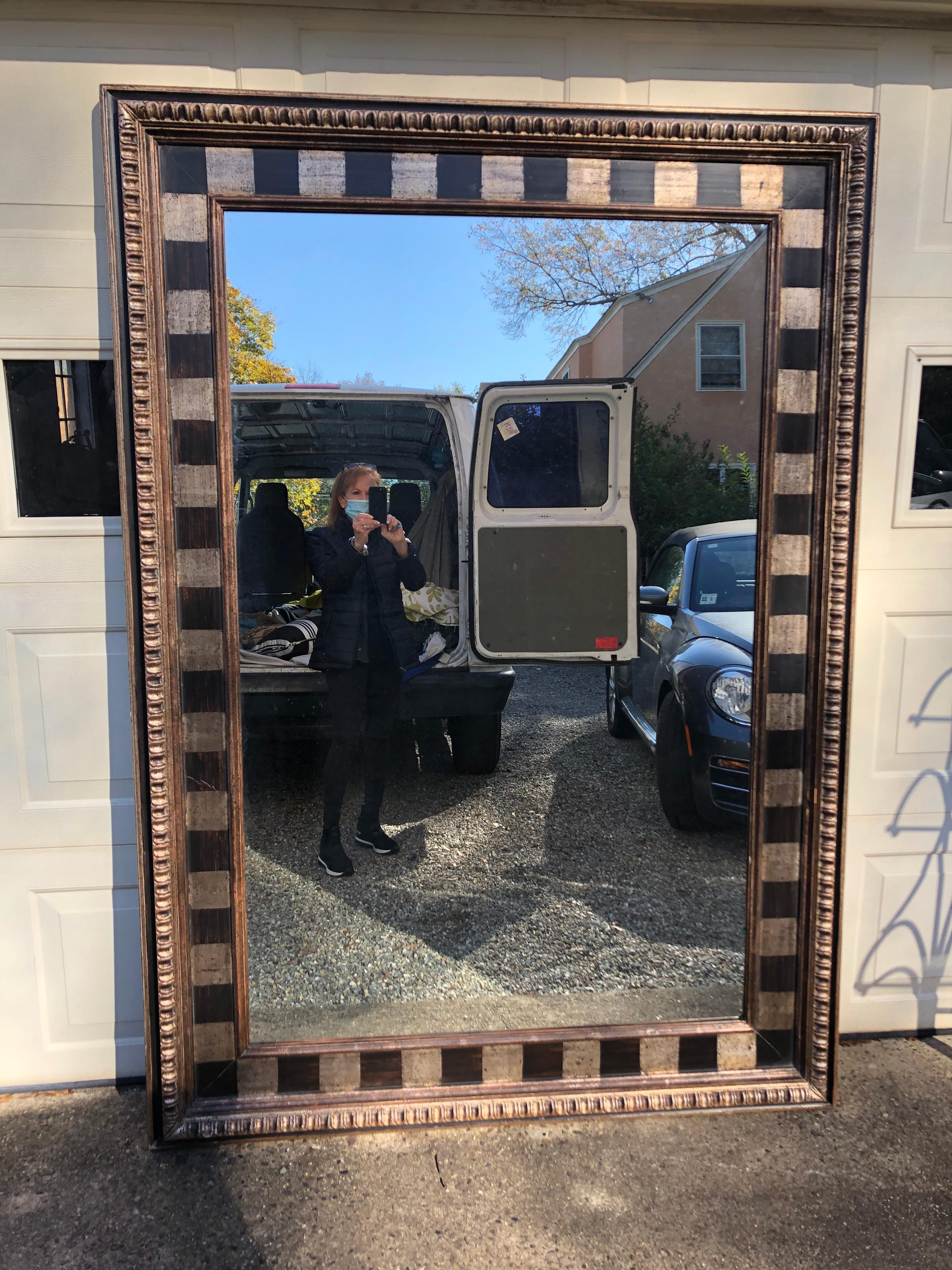 A very dramatic huge custom mirror having a black and white painted checkerboard with carved silver gilt wood, aged gold and ebonized frame. The back has a French cleat rigged for hanging horizontally, but could be oriented vertically.