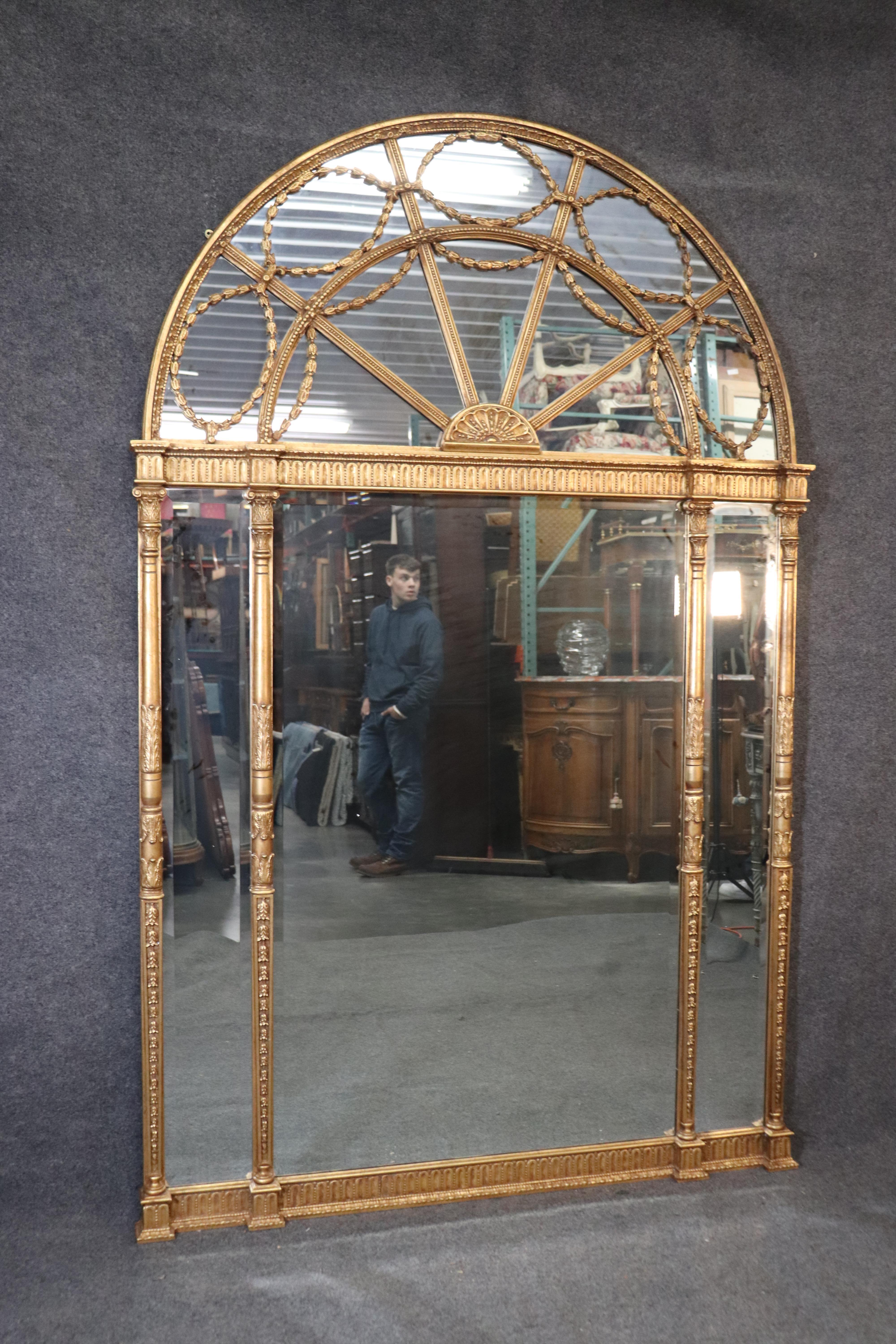 This is a massive and extremely beautiful mirror that has all of the finest carved details and lustrous gold leaf along with a fantastic design. The mirror is 91 tall x 58 wide x 3 inches thick.