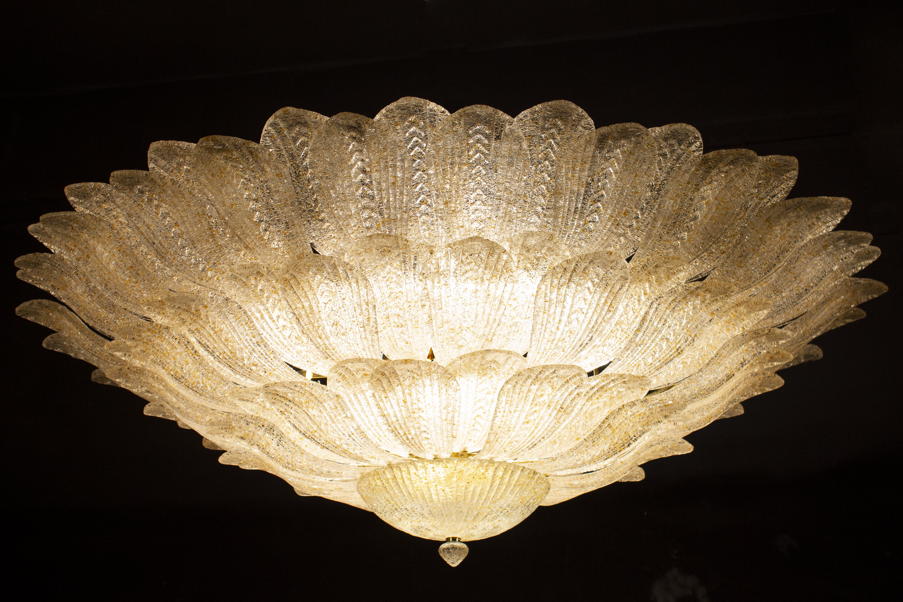 This striking ceiling light is realized in pure Murano glass, each chandelier consists of an incredible number of leaves with gold intrusion.
Gold-plated frame with 18 E 27 bulbs spread a magical light.
Available also a pair.
By Galleria