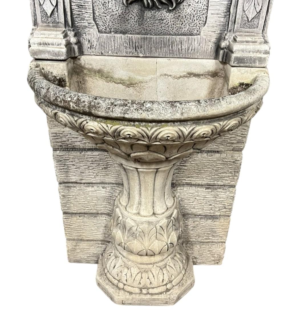 Te presentamos una extraordinaria fuente monumental de estilo griego en piedra reconstituida de mediados del siglo XX. Esta magnífica pieza está ricamente adornada con intrincadas esculturas y presenta un llamativo caño con cabeza de león, lo que la