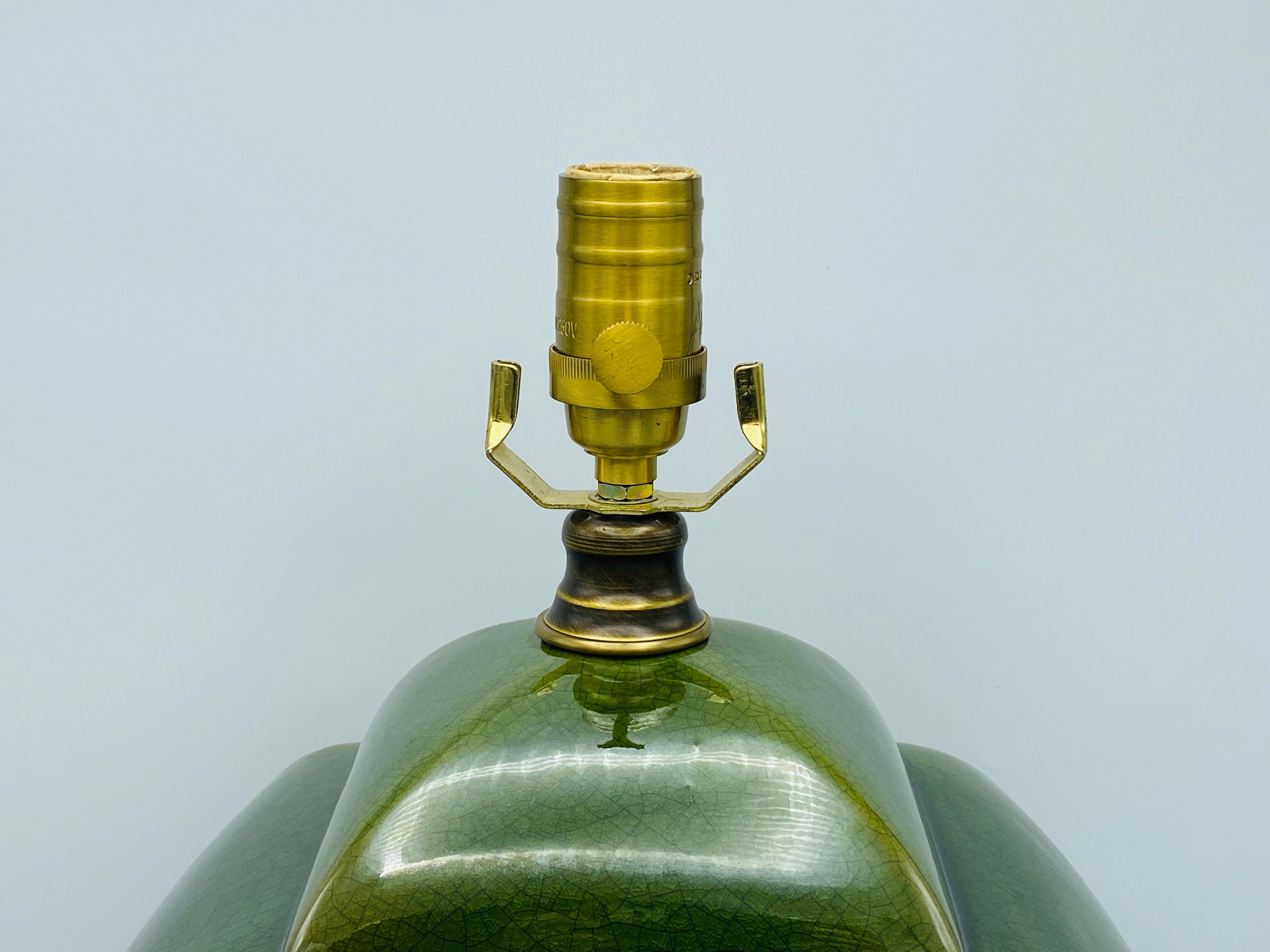 Listed is a gorgeous, monumental green crackle-glazed ceramic jar lamp, circa 1980s. This substantial lamp has an incredible finish, adding a natural feel to the piece. Luxurious brass socket and switch, with an extended length cord. Marked along