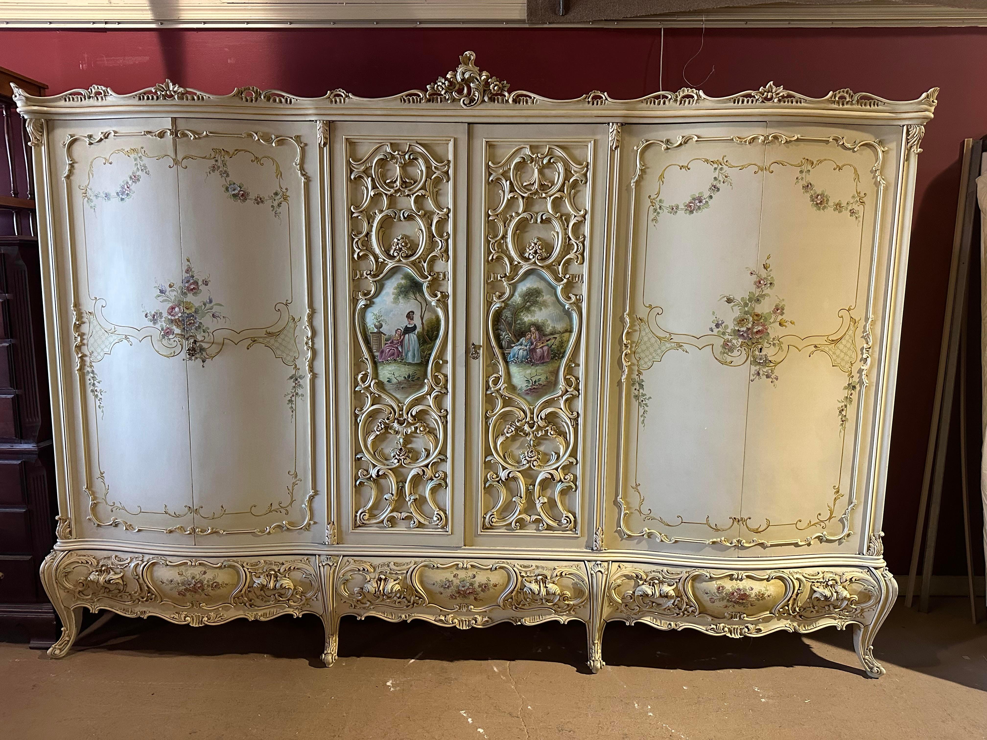 This is a monumental sprawling armoire at 121 inches wide. The armoire features beautiful hand-painted maidens and classical scenery and carving and just promotes a sense of majesty and romance. The colors are muted and in the pastel family and