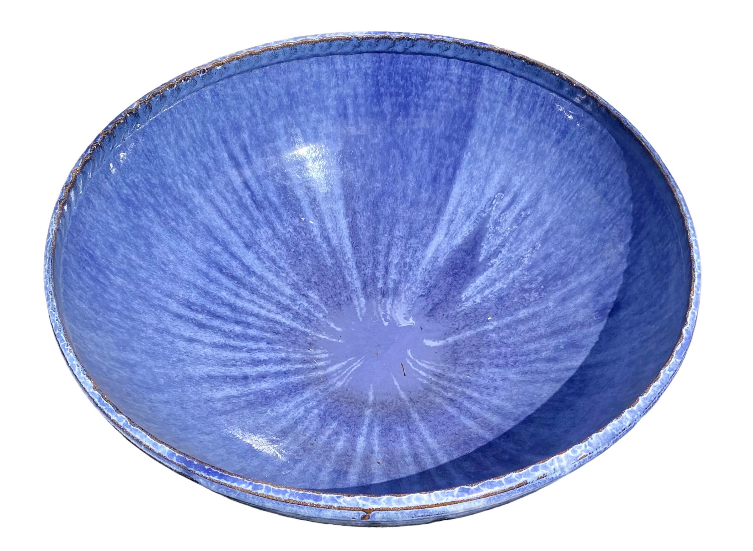 A stunning and monumental hand thrown and glazed terracotta bowl in shades of cerulean and lapis blues, hand made in the New Orleans studio of Alex and Cindy Williams.

Award-winning artisans Alex and Cindy Williams have created hand-crafted pottery