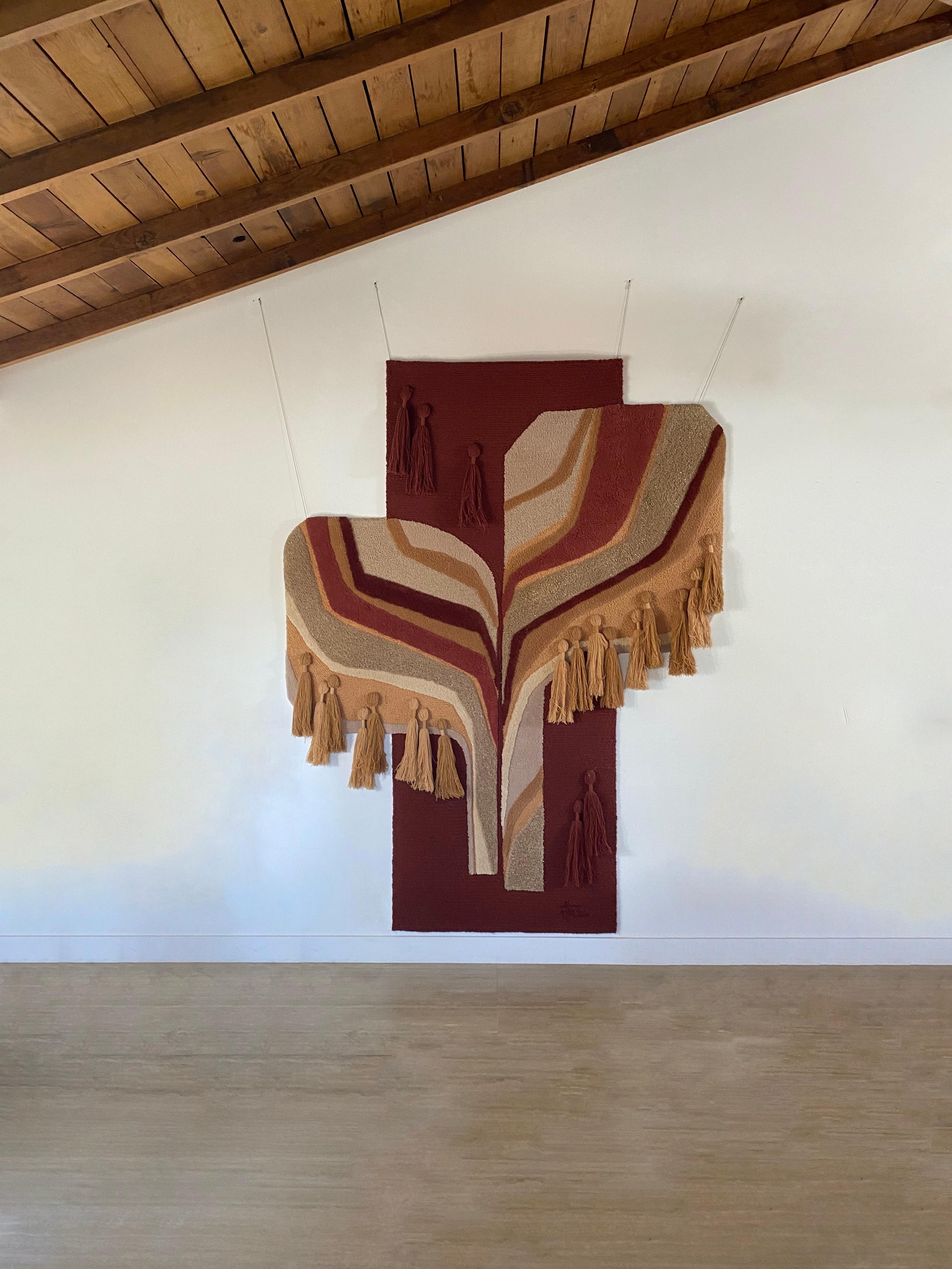 This monumentally sized fiber art tapestry was handmade by Tekima, Germany in circa 1970. The stunning use of materials and colors create a vibrant and unique design supported by four wires. The main colors of burgundy, browns and greys are accented