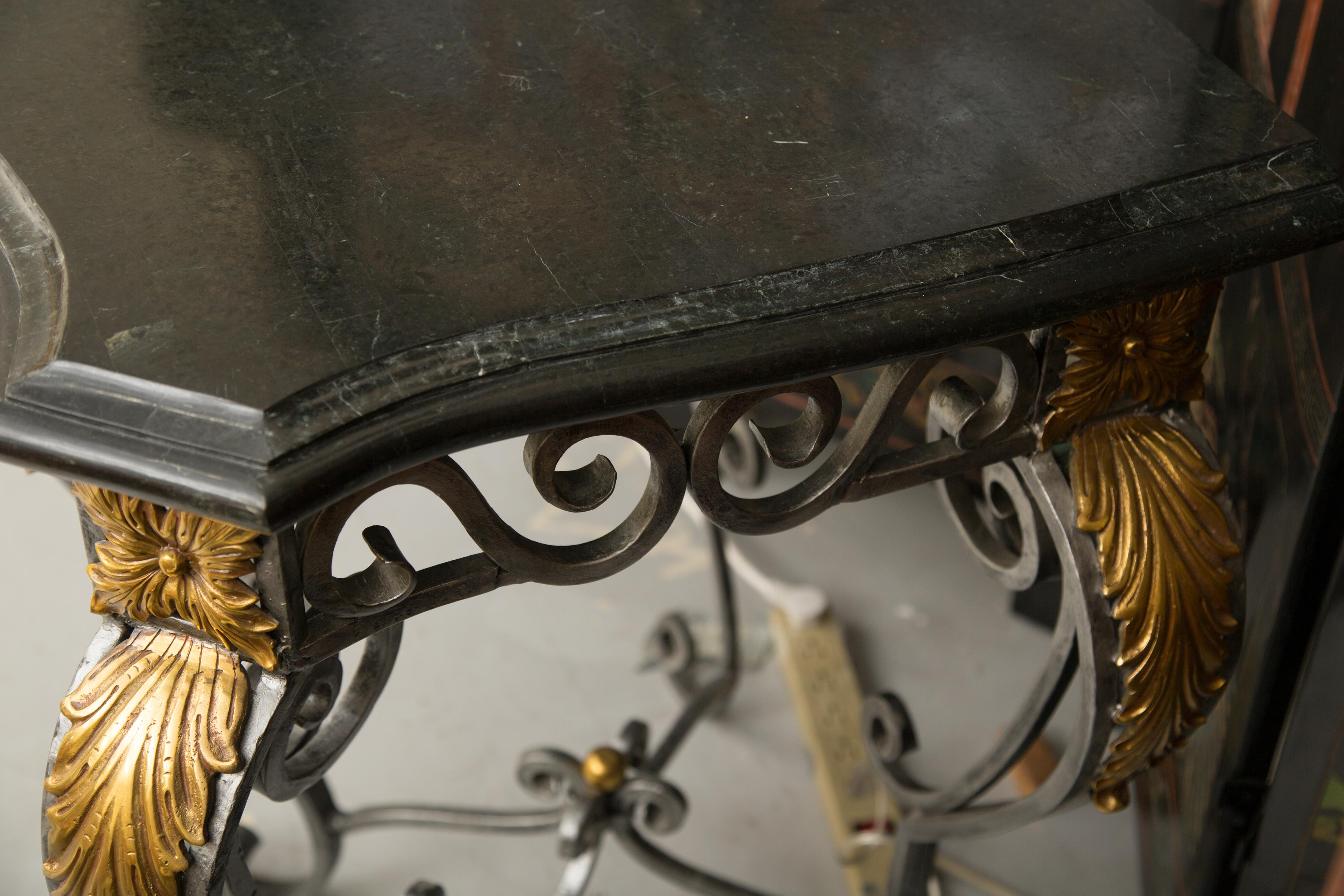 This is an impressive iron serpentine shaped console table with a scrolled design and decorated with gilt mounted acanthus leaf decoration. The table has an elaborate form of scrolls and curls which offers a sophisticate element for ones interior.