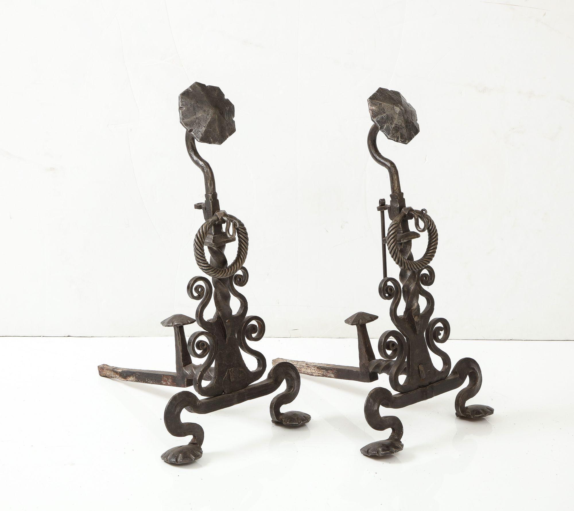A monumental pair of iron andirons with wonderful hand forged scrolled body and legs, topped by bold octagonal finials on gooseneck heads with finely wrought rope-effect iron rings below. Very large and substantial. American, circa 1880.