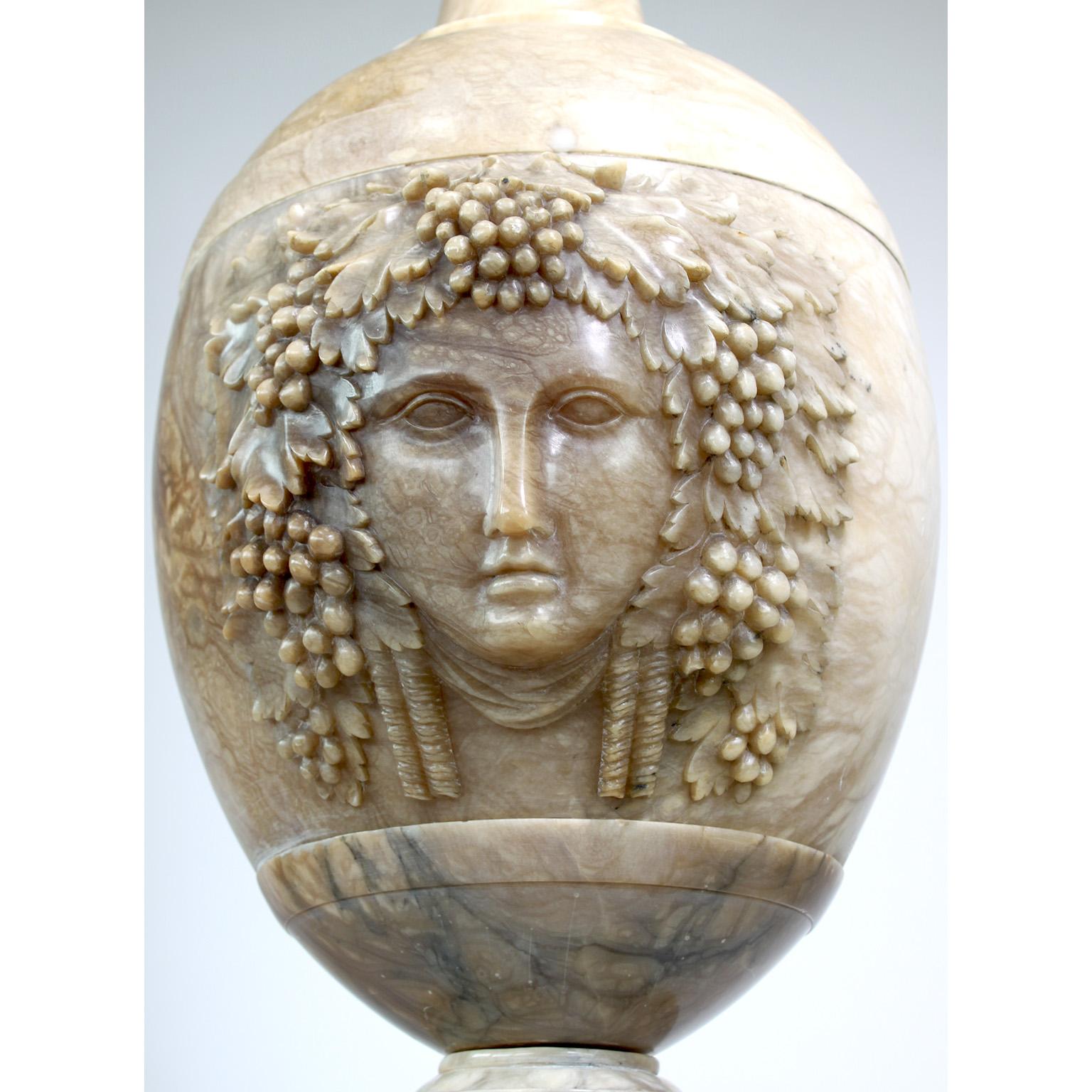 A very fine and monumental Italian 19th century Renaissance Revival Style Carved Alabaster figural ewer or urn. The impressive ornately carved alabaster ovoid body centered with an allegorical female mask crowned with grape vines and leaves, the top