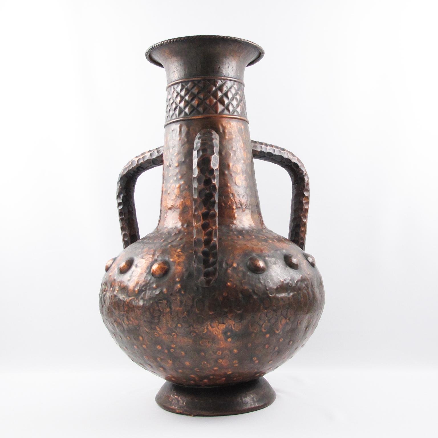 Este monumental jarrón urna con asas y forma de balaustre fue fabricado a mano en Italia hacia 1960. Los detalles trabajados a mano en el cobre, junto con su hermosa pátina, confieren a esta vasija un atractivo único. Este importante jarrón presenta