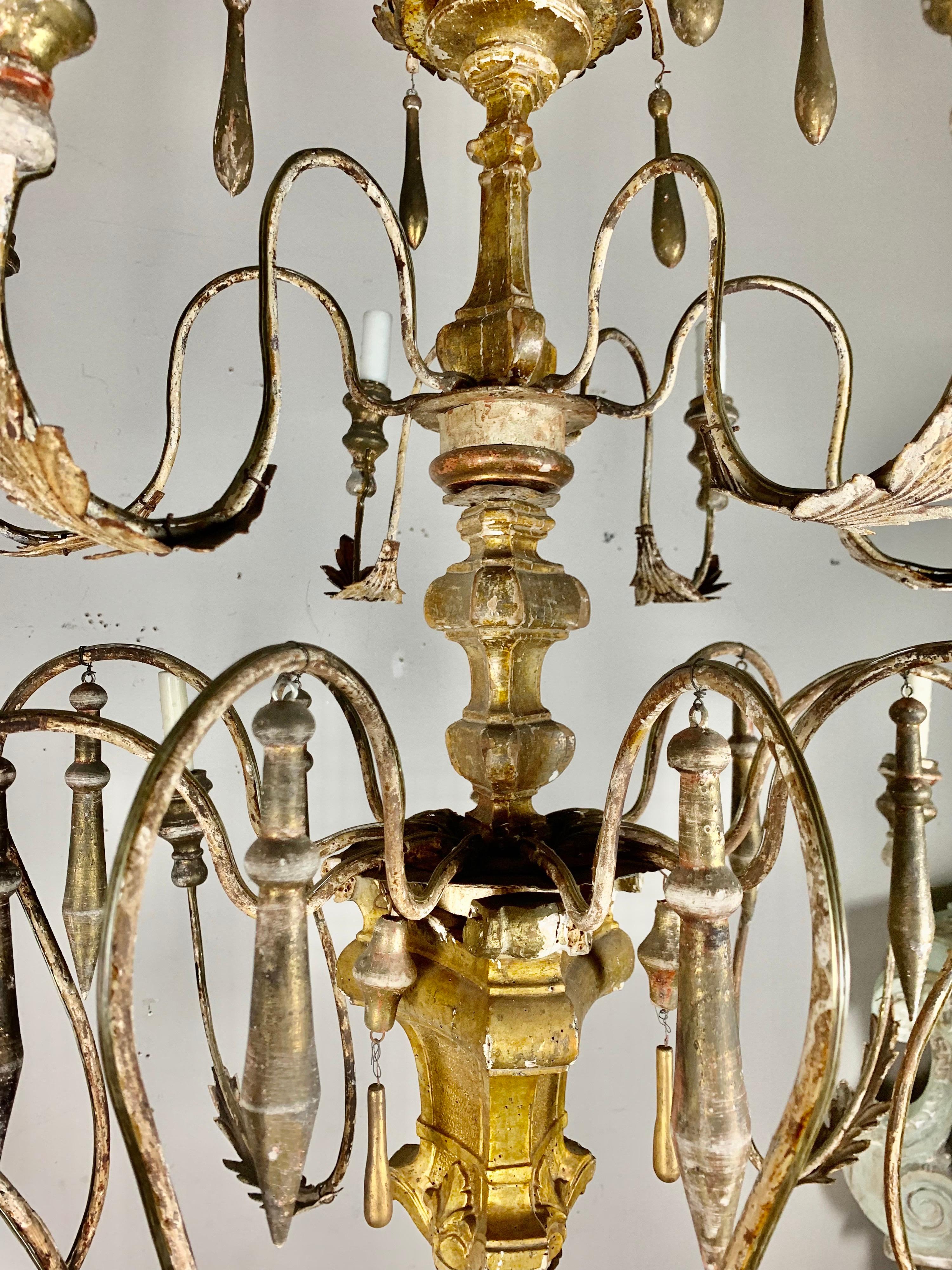 Italian giltwood & metal eight light chandeliers with giltwood drops throughout. The chandelier has a beautiful patina throughout. The chandelier is newly wired with drip wax candle covers. Includes chain & canopy.