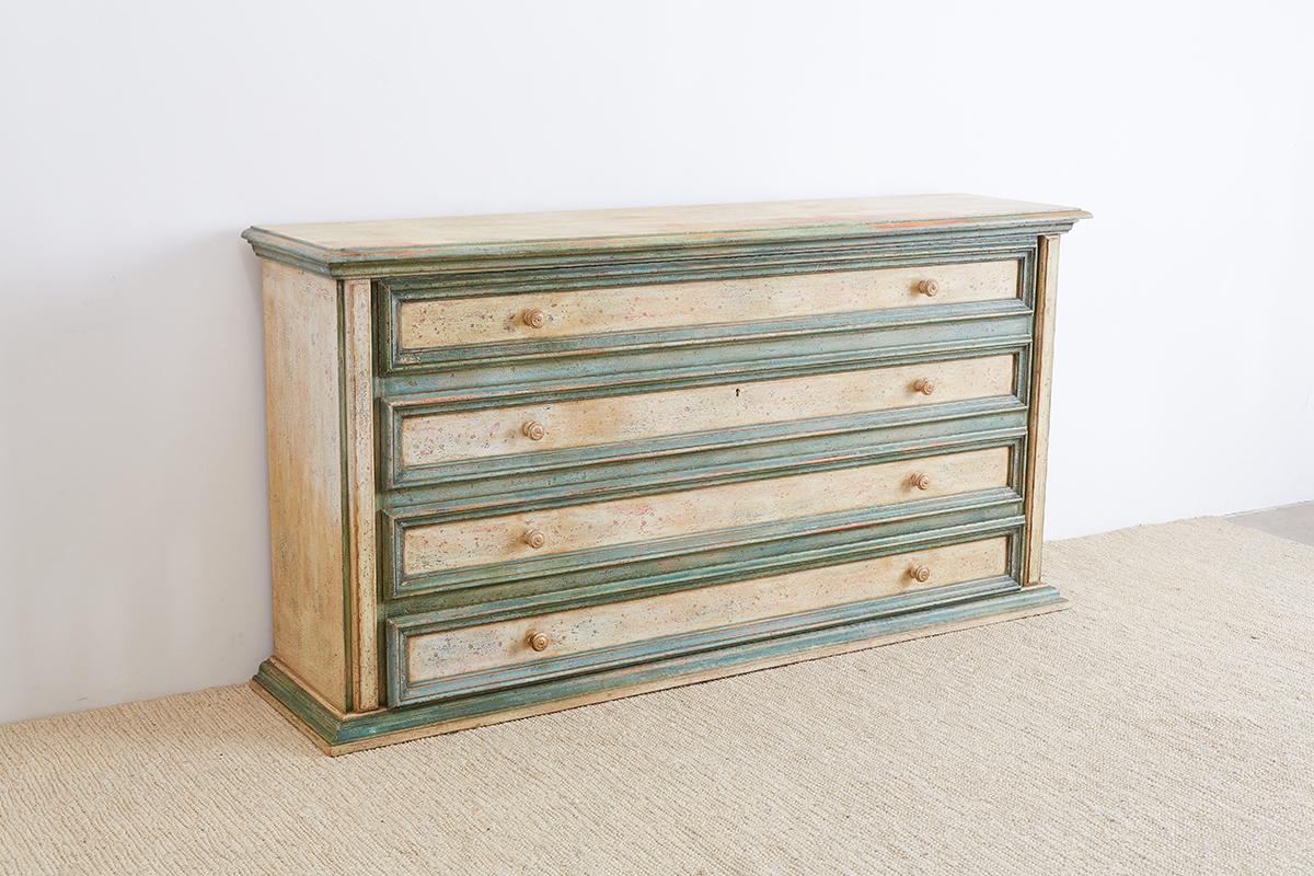 Monumental Italian provincial chest of drawers or dresser sideboard featuring a lacquered finish. Fronted by four large drawers each having a 6.5 inch deep interior and two wooden pulls. Finished in a cream and green lacquer with a beautiful