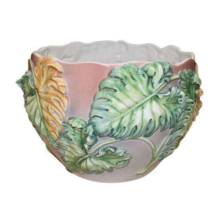 Cette jardinière en céramique polychrome à motif tropical est un exemple rare et exceptionnel de majolique italienne. Elle est émaillée dans une teinte rose pâle, avec des détails appliqués sur le front de palmiers verts et jaunes. Le dessus est