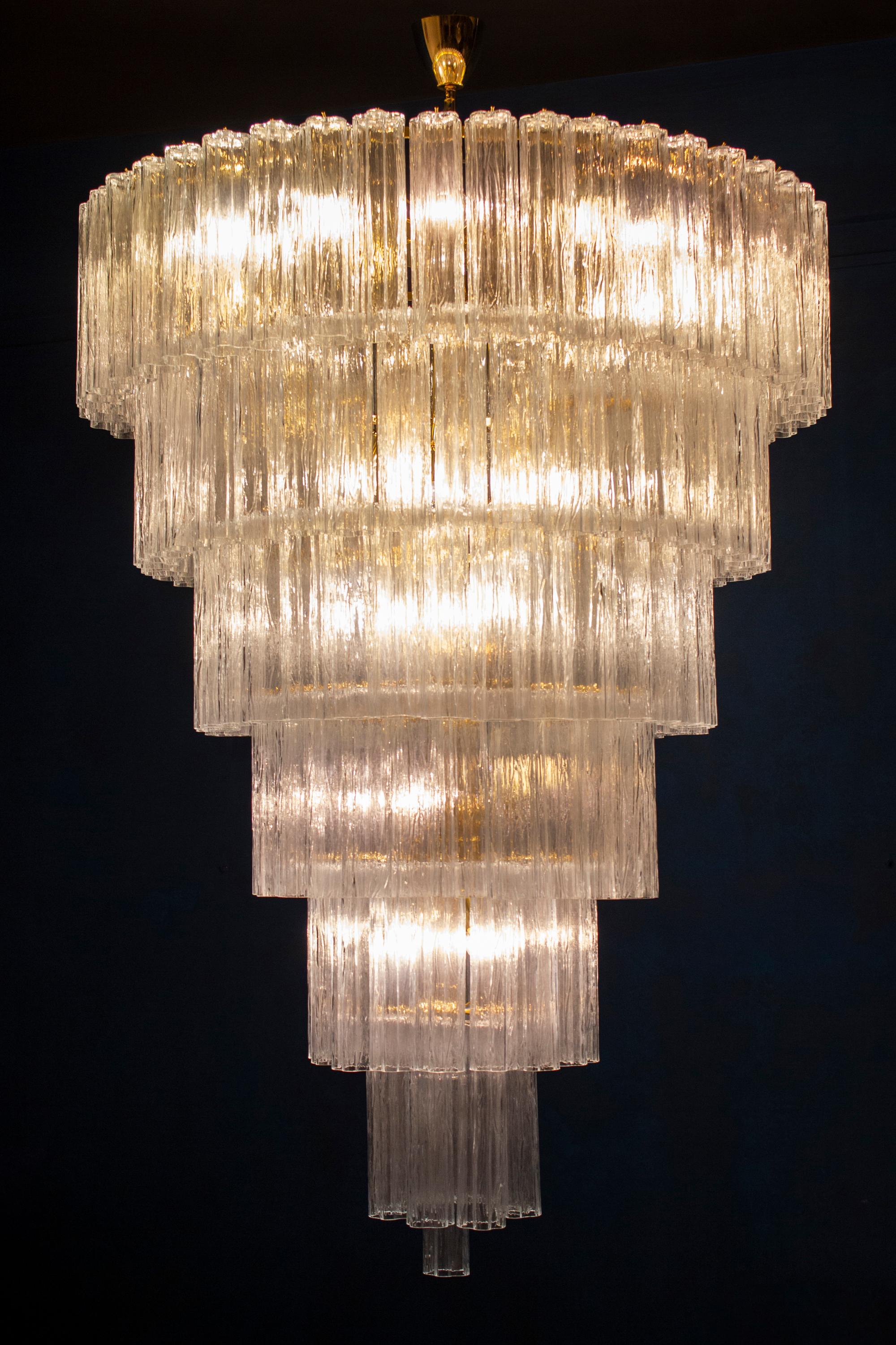 This extraordinary chandelier on 7 levels composed by 165 'Tronchi' 30 cm high glasses.
 Brass frame.
Eighteen-light bulbs E 14.
Measure: Height 175 cm without chain.
Available also a pair.
 This light fixture can be disassembled and the glasses