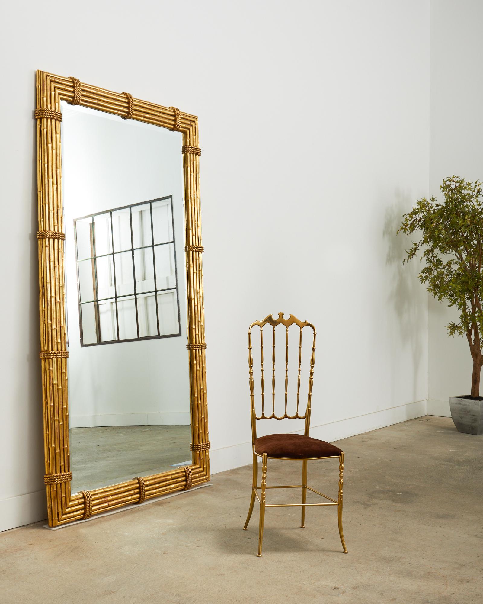 Grand 20th century Hollywood Italian Regency floor mirror made on a monumental scale. The mirror features a 5.5 inch thick wood frame hand-carved by Italian artisans with faux bamboo poles bundled together with faux rope strapping. The frame was