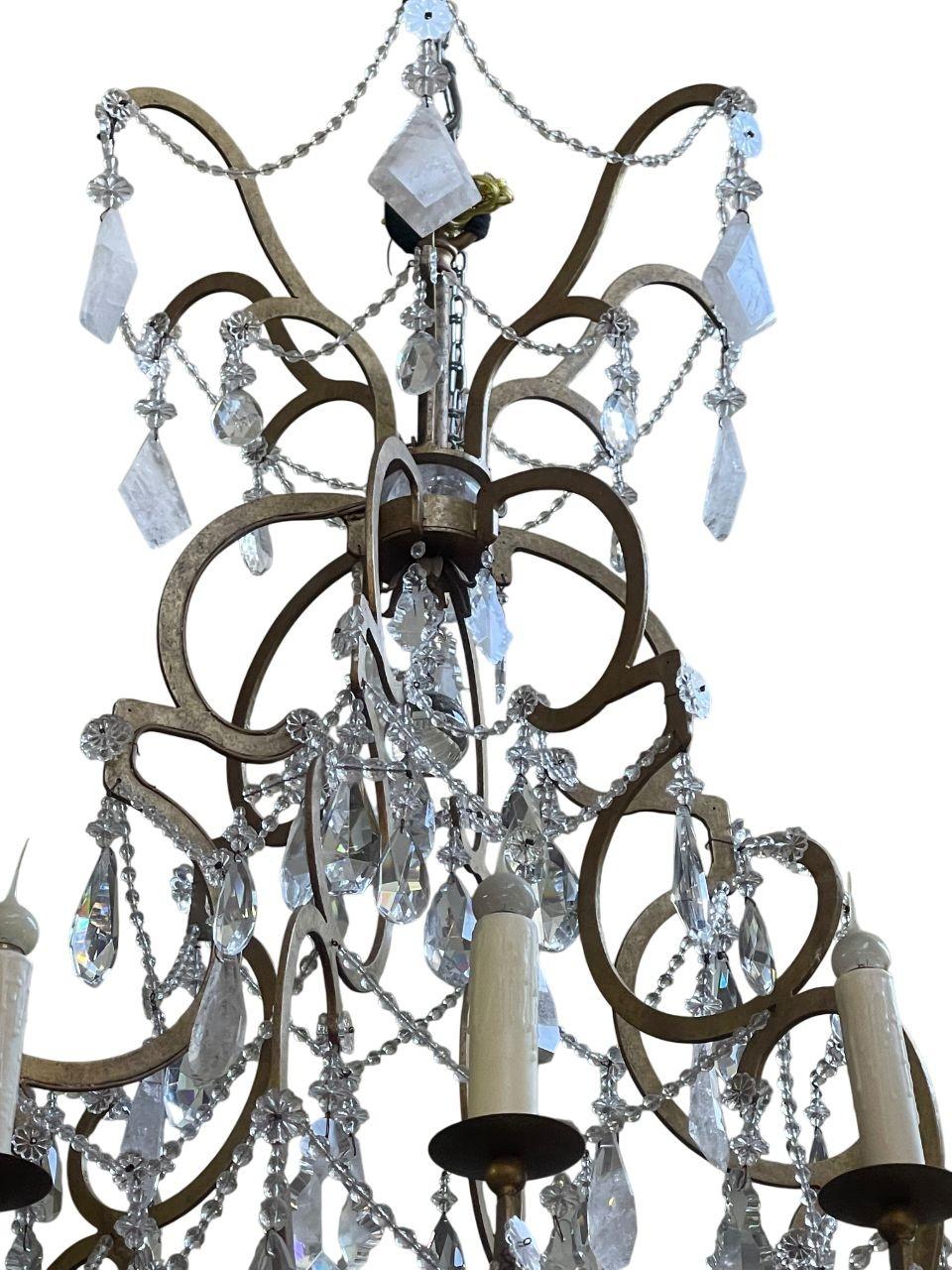 A breathtaking and monumental 20th-century Italian chandelier crafted in wrought iron and richly adorned with an abundance of crystal & natural rock crystal. This grand statement piece showcases exceptional craftsmanship, with elegant scrolling