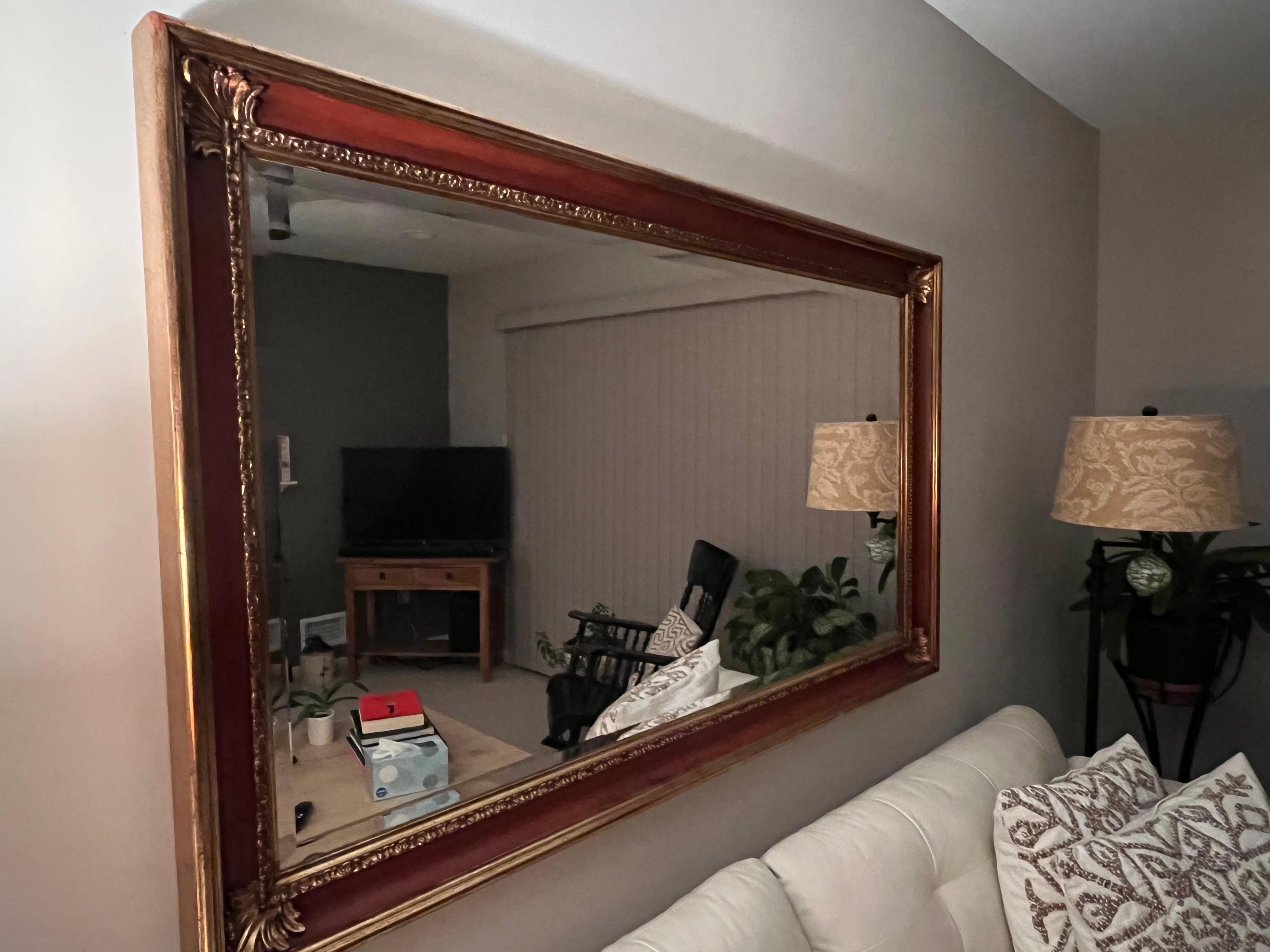 Impressive rich looking very large rectangular bevelled mirror having warm walnut framed with exterior gilt wood periphery around mirror and wood frame with fancy fleur di lis type decoration in each corner.  There is wonderful red underpaint