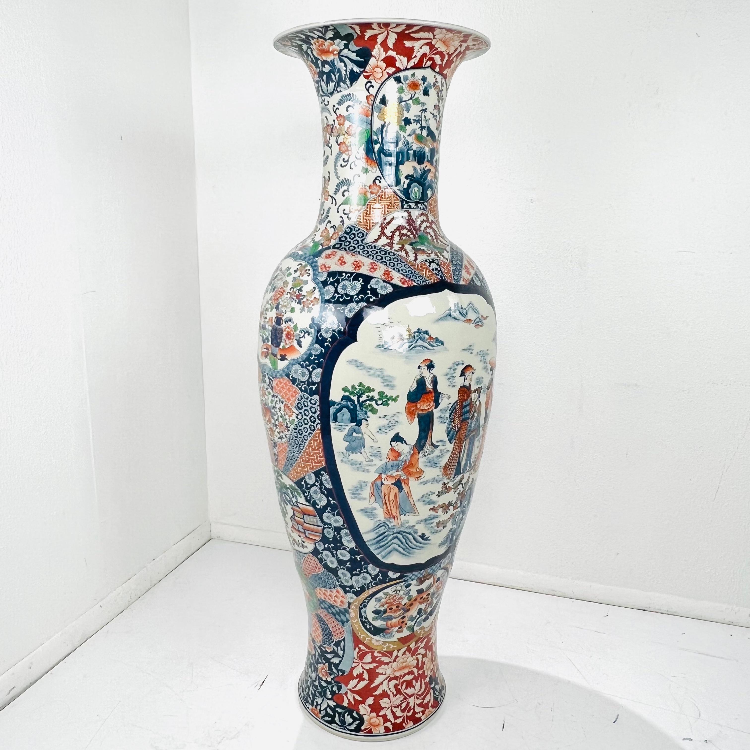 Splendido e monumentale vaso da terra in porcellana Imari giapponese del periodo Meiji (1868-1912), caratterizzato dal classico sfondo blu e bianco con sovraccoperta dorata, arancione, rossa e verde. Delicati pannelli dipinti a mano raffigurano