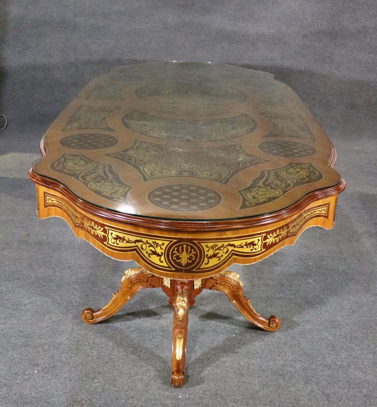 This is a spectacular brass inlaid dining table in the style of Andre Boulle of France. The brass inlaid surfaces are not damaged or lifting as these often do. The table has a small chip in the glass which can be polished out and minimized if you
